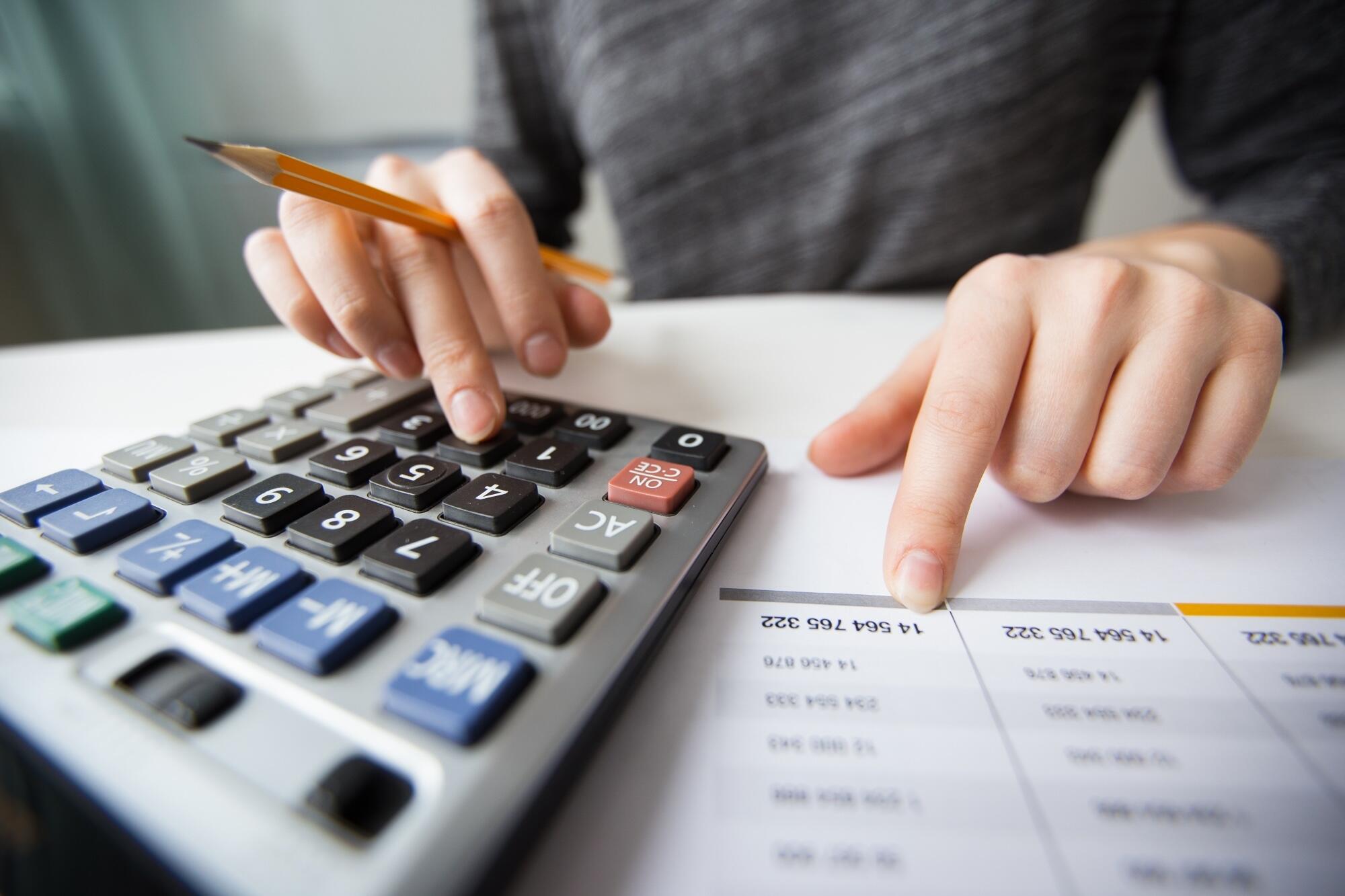 Une personne est en train de faire des calculs avec une calculette.