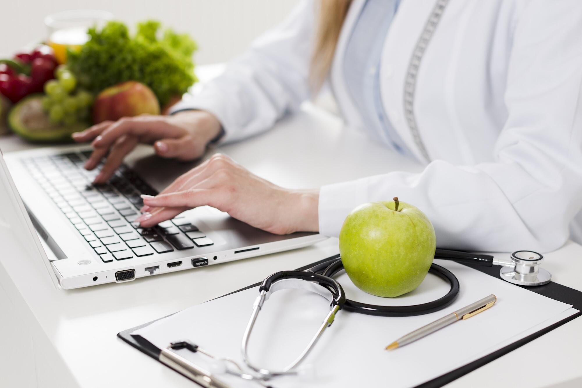 Un médecin est en train de taper à l'ordinateur avec une blouse blanche