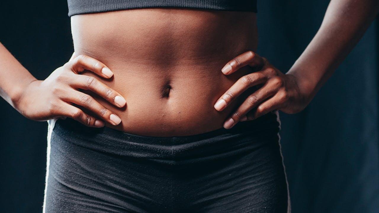 Focus sur le ventre d'une femme mains sur les hanches