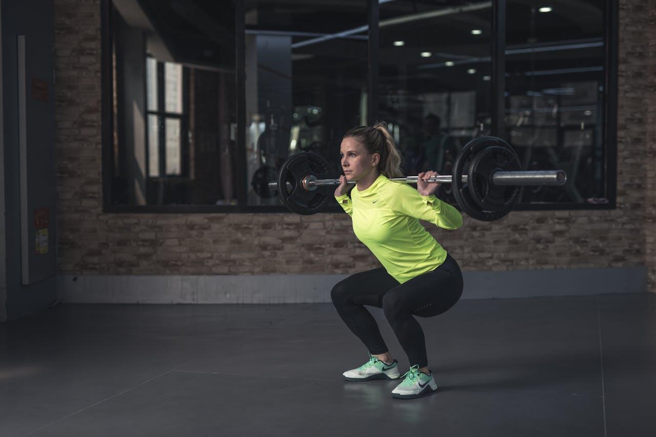 Une jeune femme qui réalise un squat à la barre.