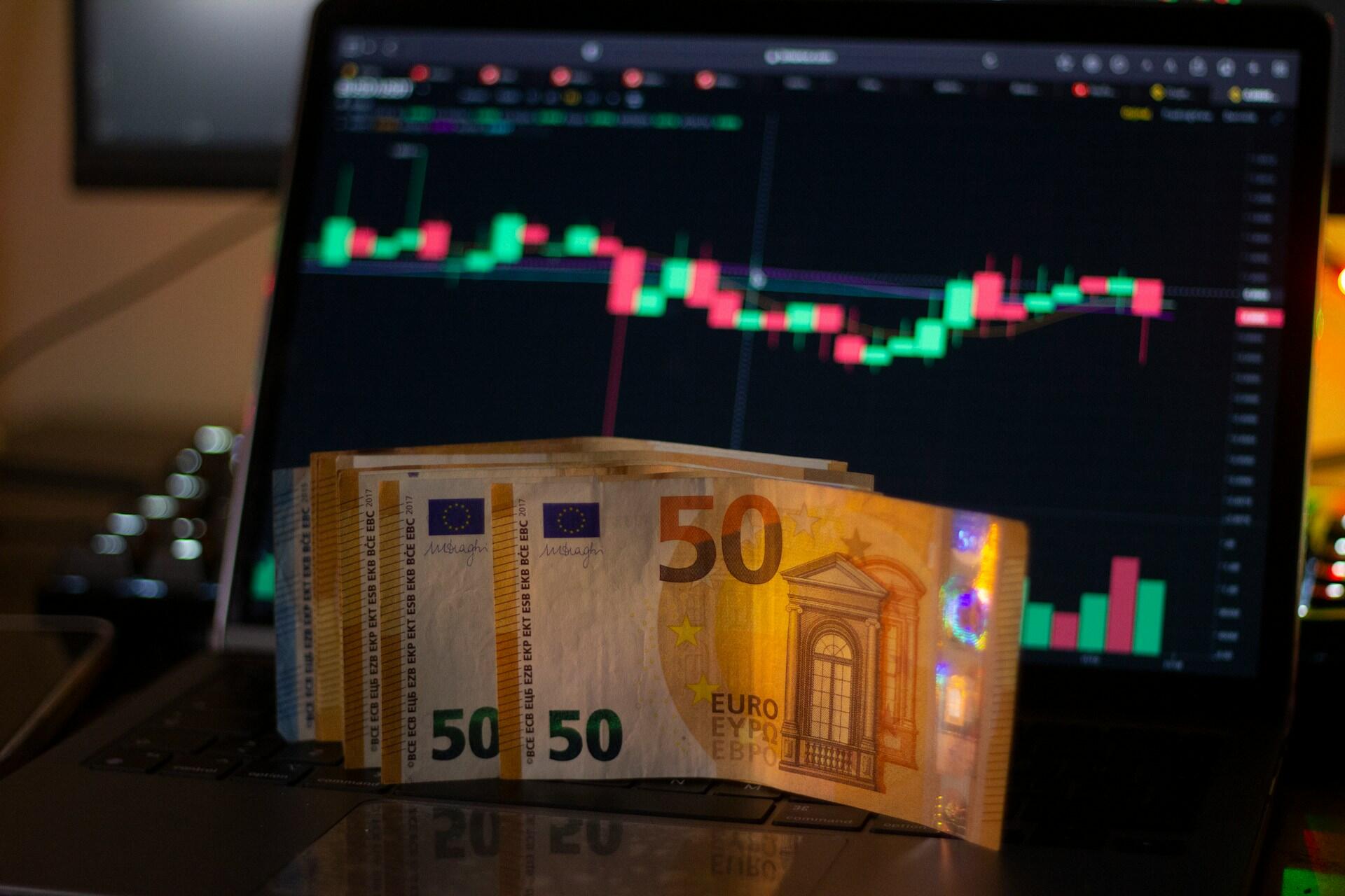 billets de 50 euros devant un ordinateur de trading