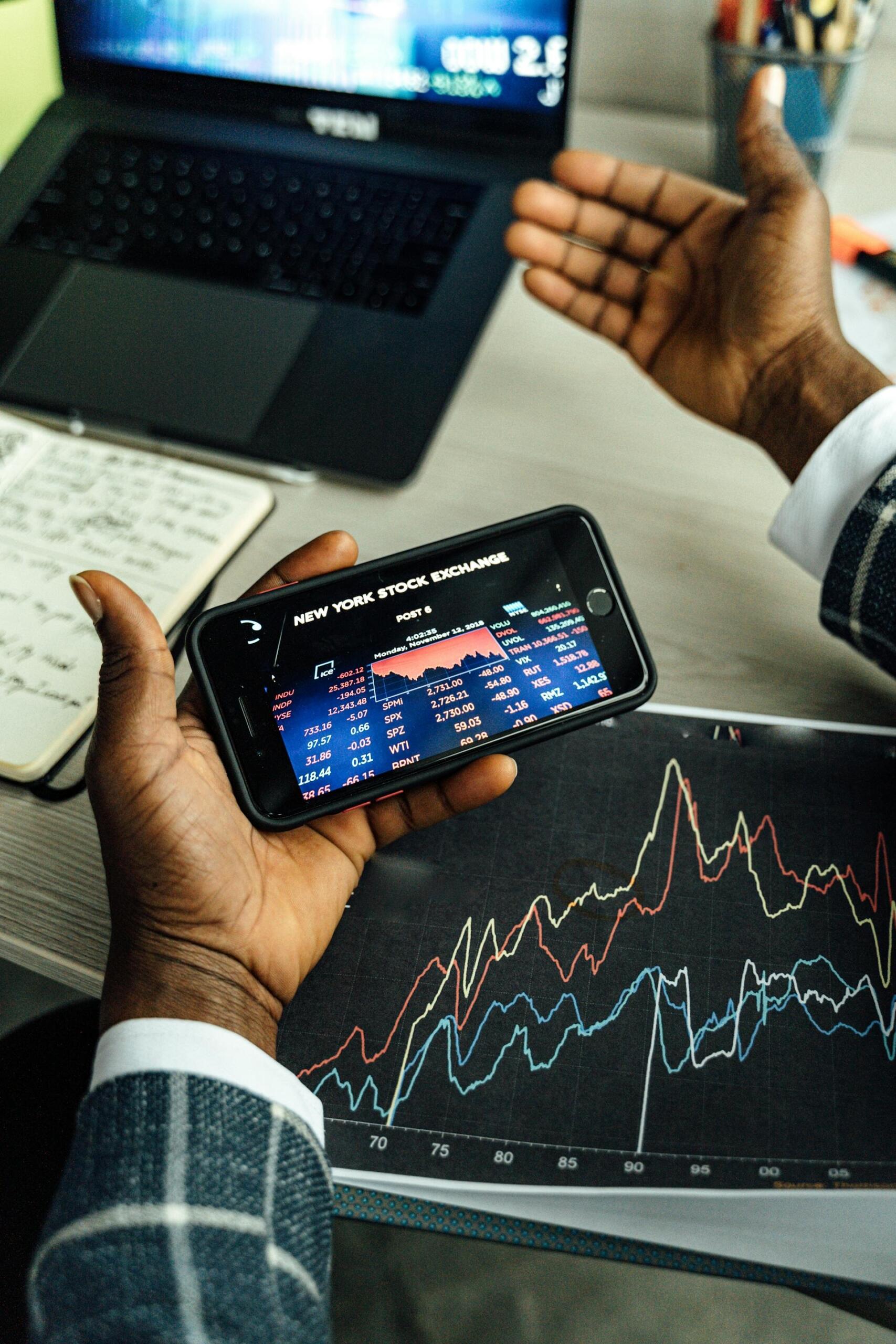 homme tenant un téléphone avec des informations de trading