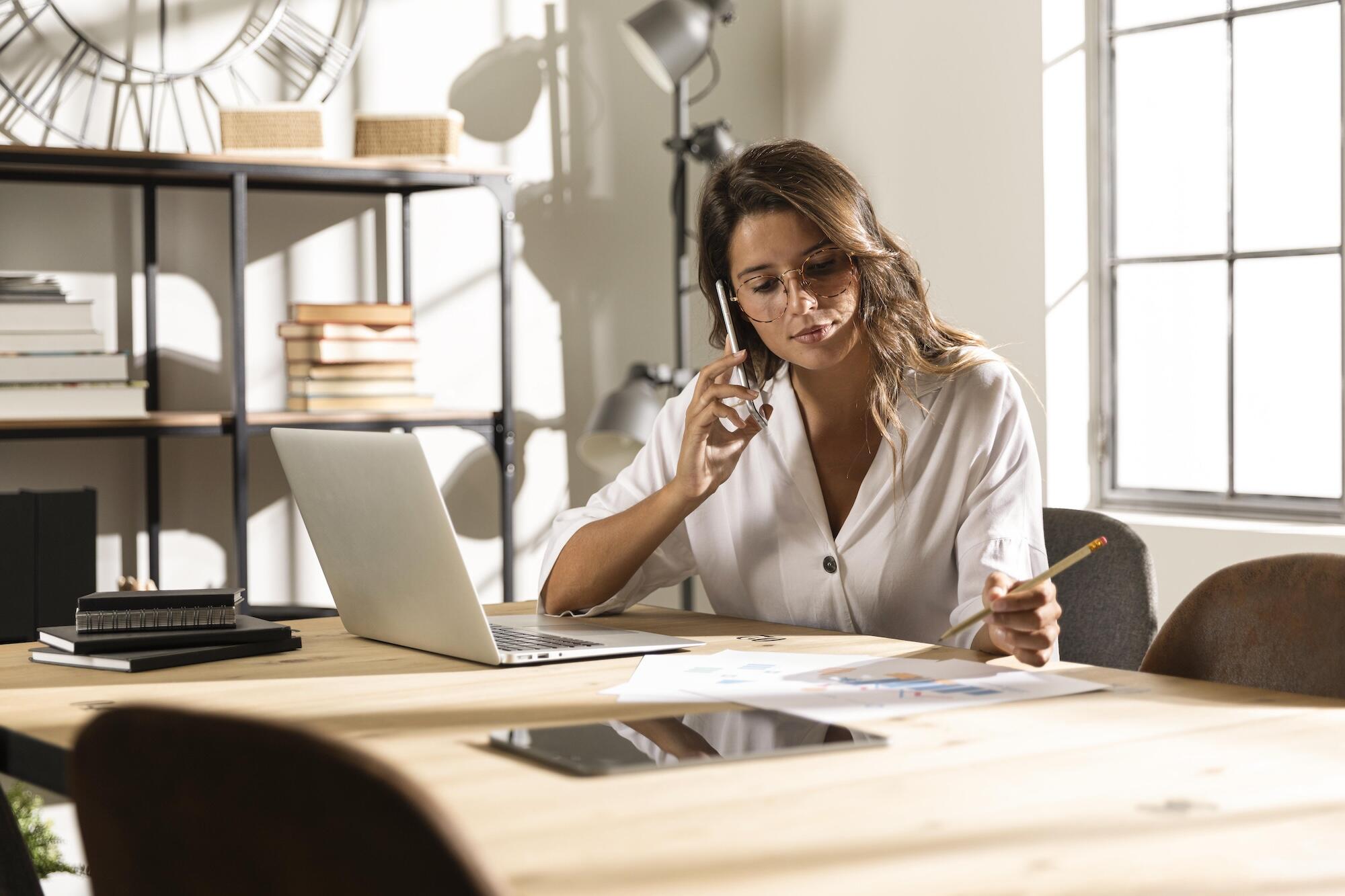 Une femme est au téléphone devant un ordinateur.