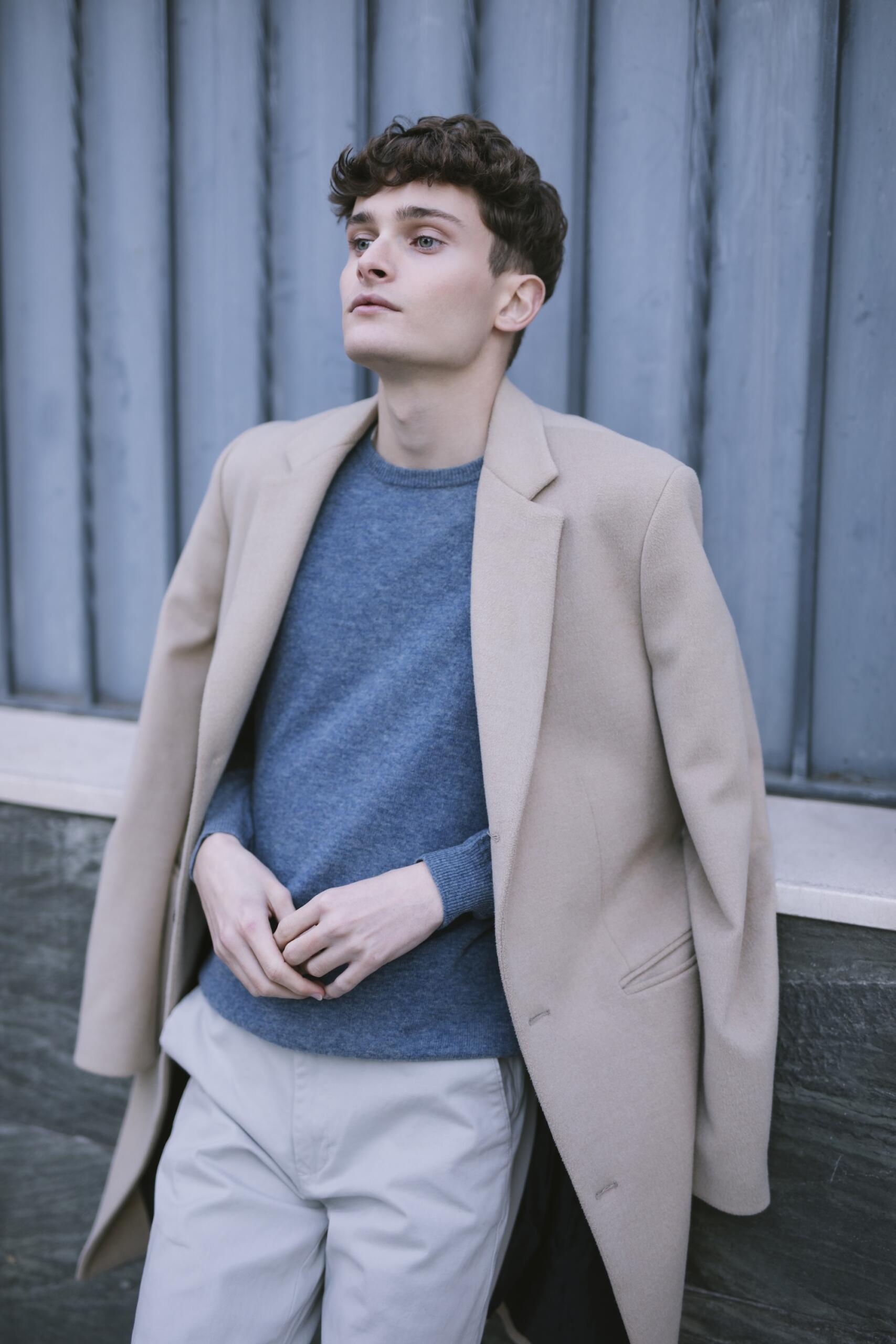 Un homme porte un blazer par dessus un pull