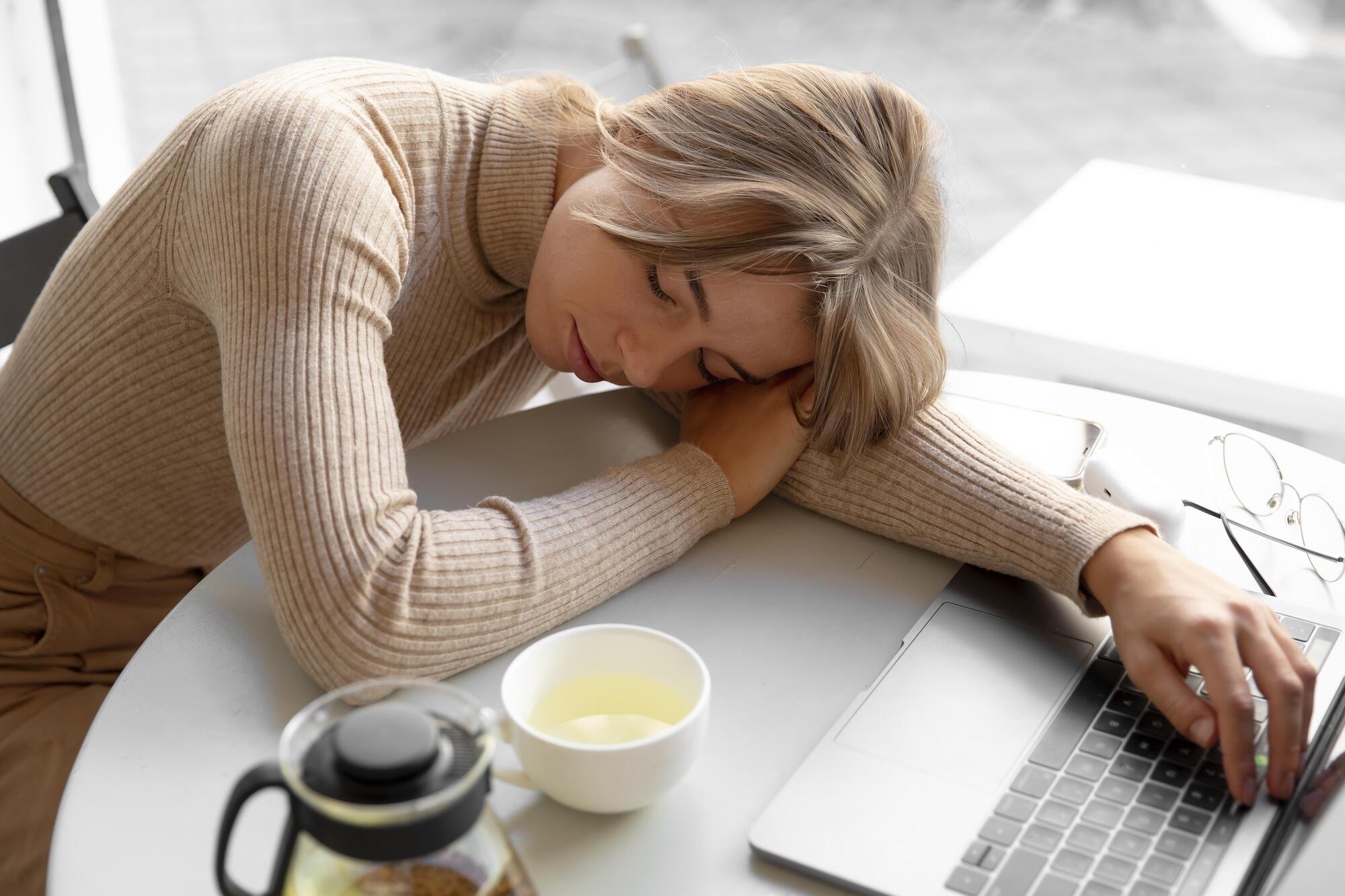 Une jeune femme est allongée sur la table devant son ordinateur