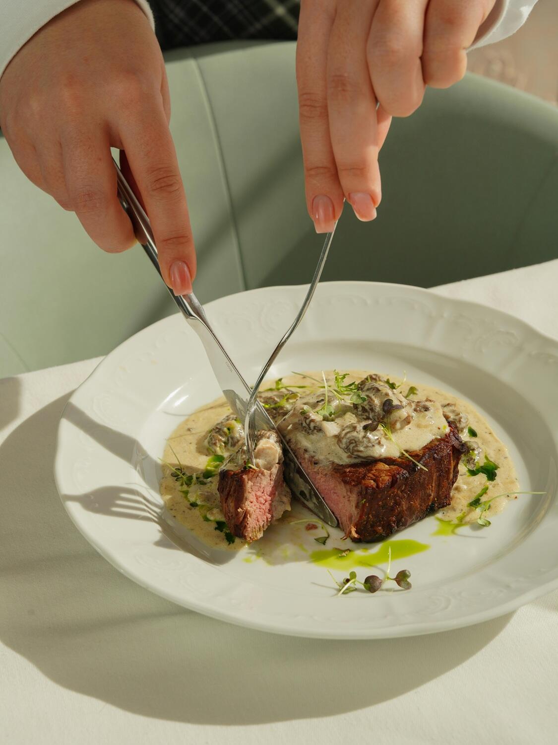 Une personne coupe un morceau de viande dans une assiette.