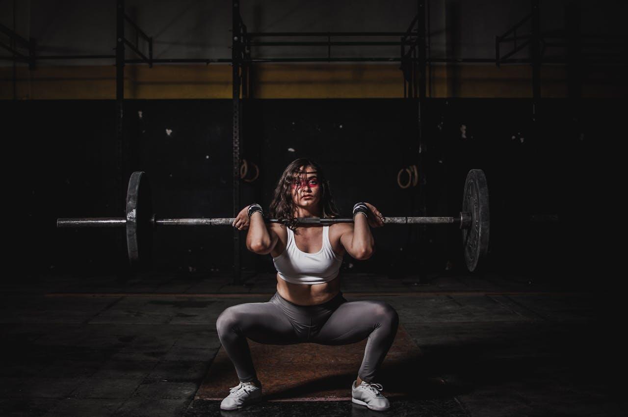 Jeune femme en squat sumo avec une barre.