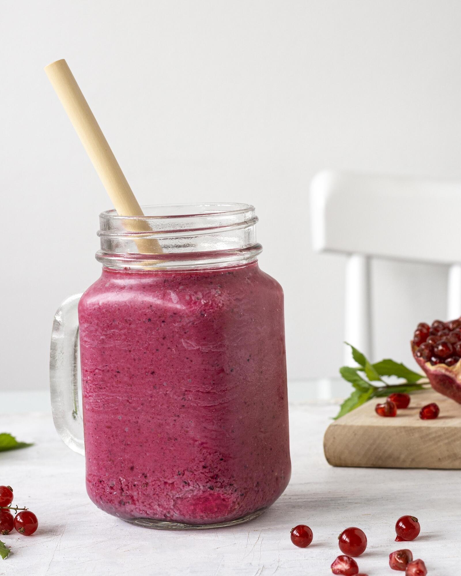 Un smoothie aux fruits rouges dans un verre avec une paille