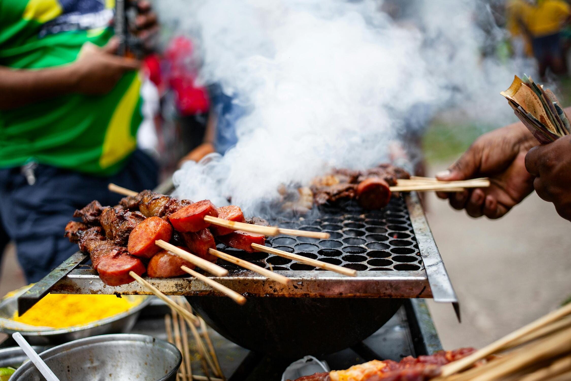 Une personne fait griller de la viande rouge.