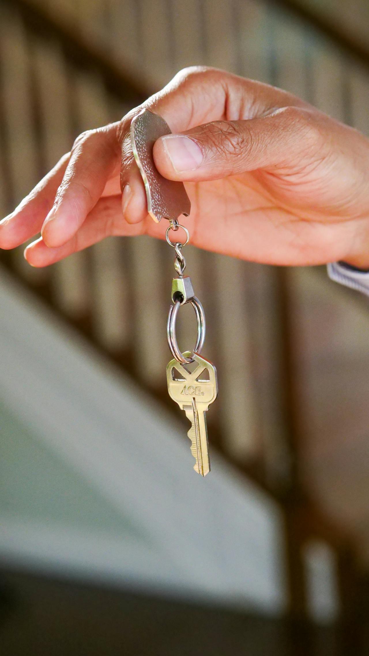 Main d'un homme tenant une clé accrochée à un porte-clés.