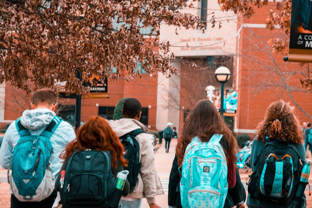 Groupe d'étudiants vus de dos portant leur sac à dos. 