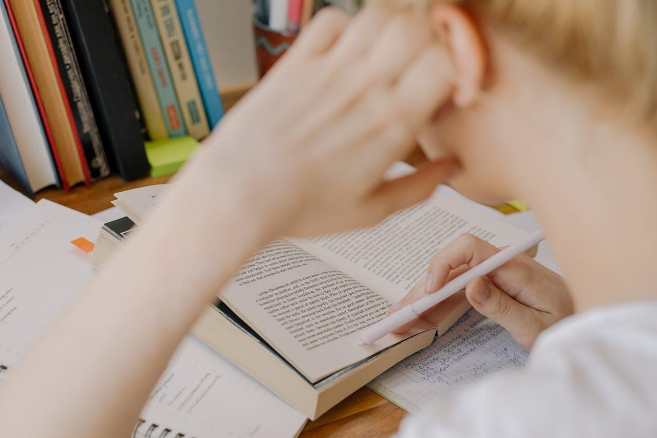 Jeune homme penché sur un livre étudiant à son bureau. 