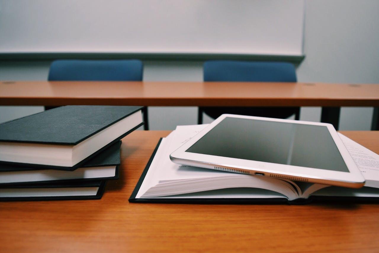 Bureaux dans une classe avec livres et iPad posés dessus.