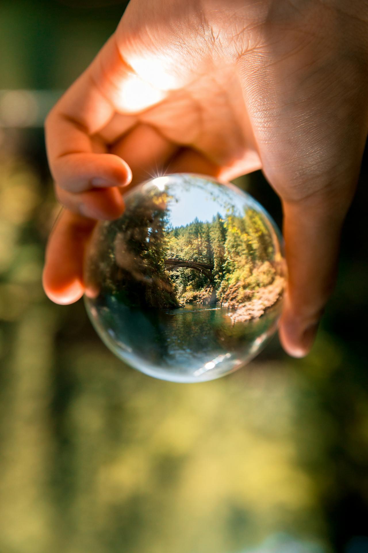Une main tenant une boule transparente dans la nature