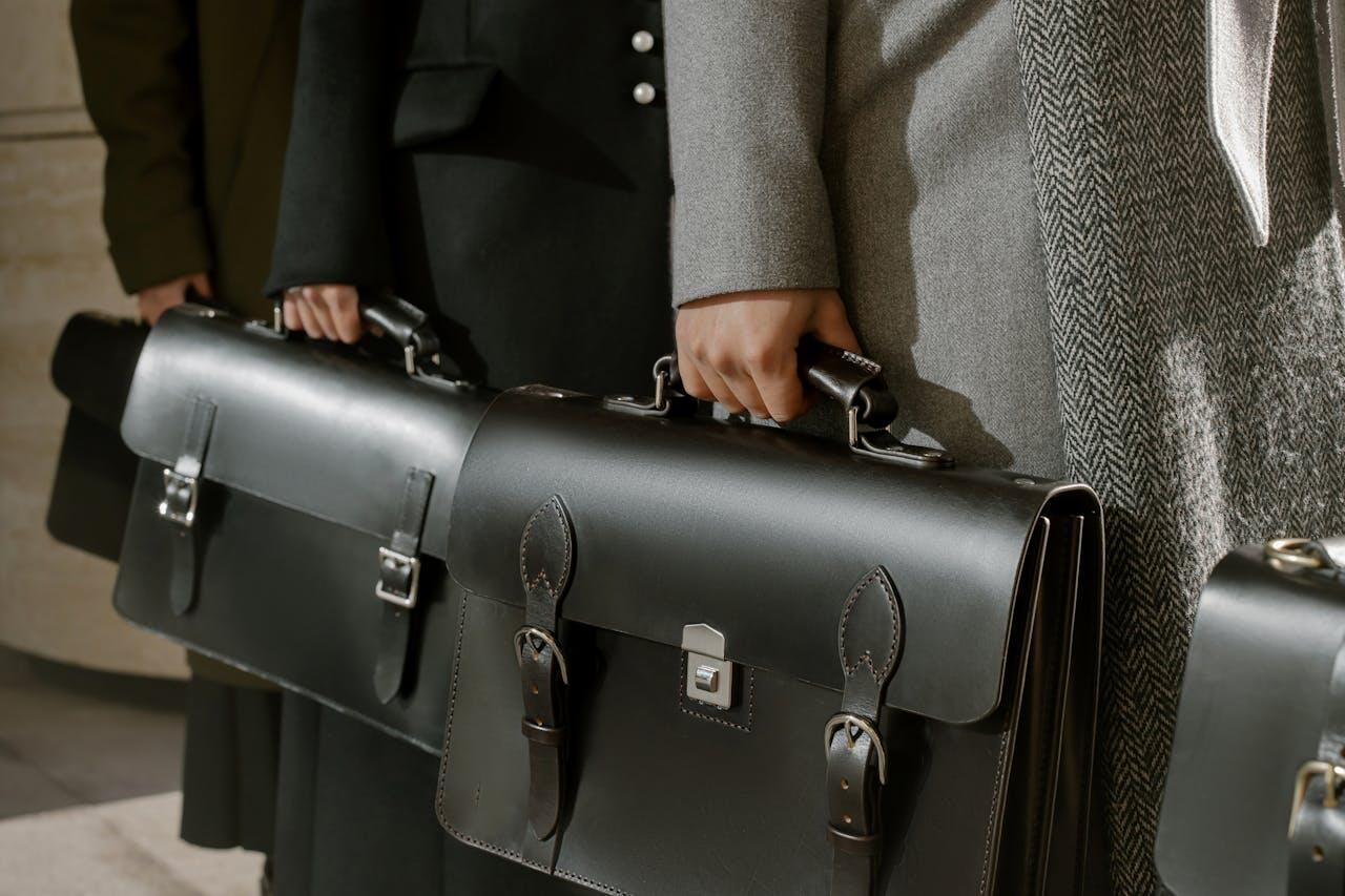 3 travailleurs en costumes portant des cartables noirs. 