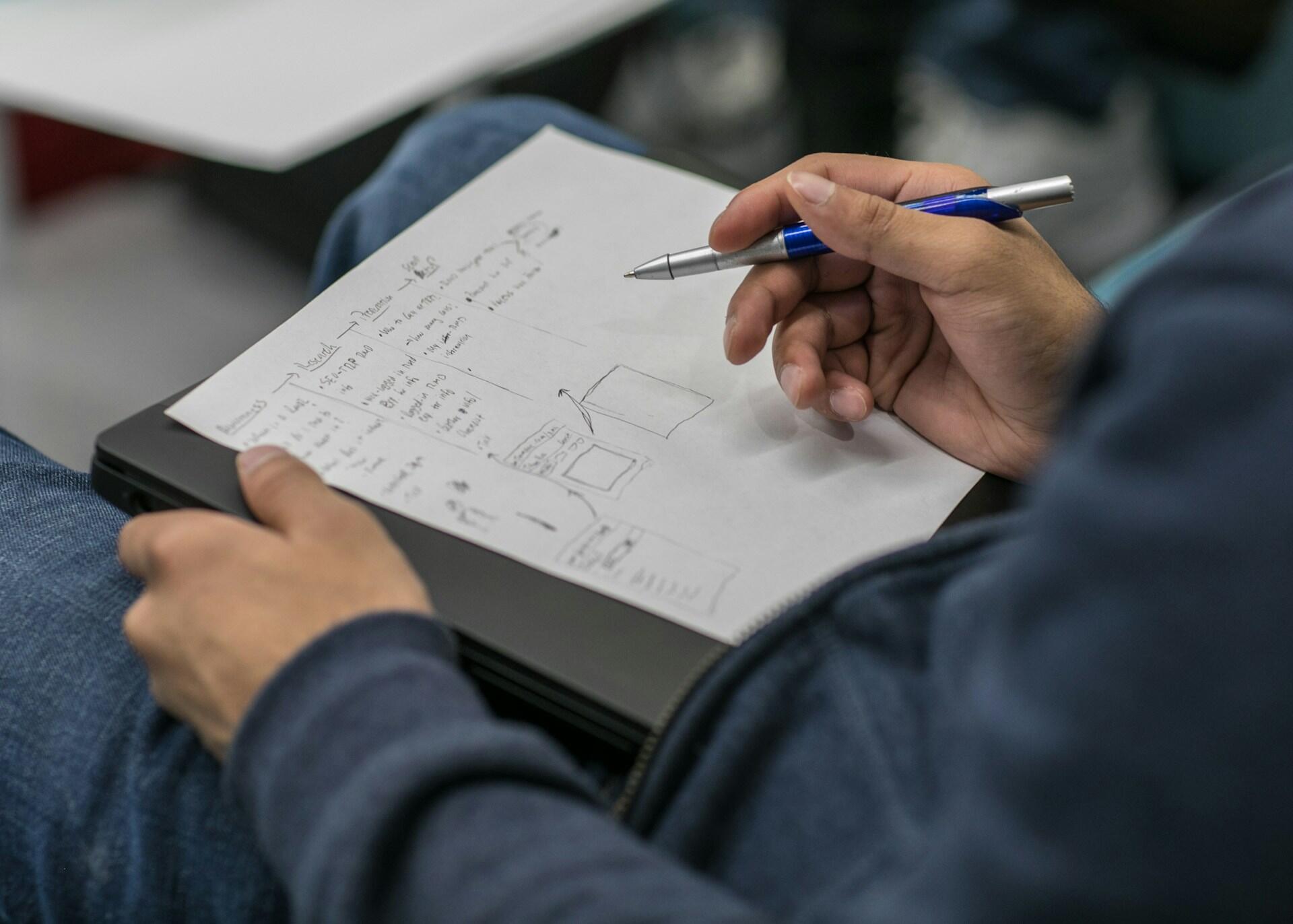 personne en train de prendre des notes en maths sur une feuille