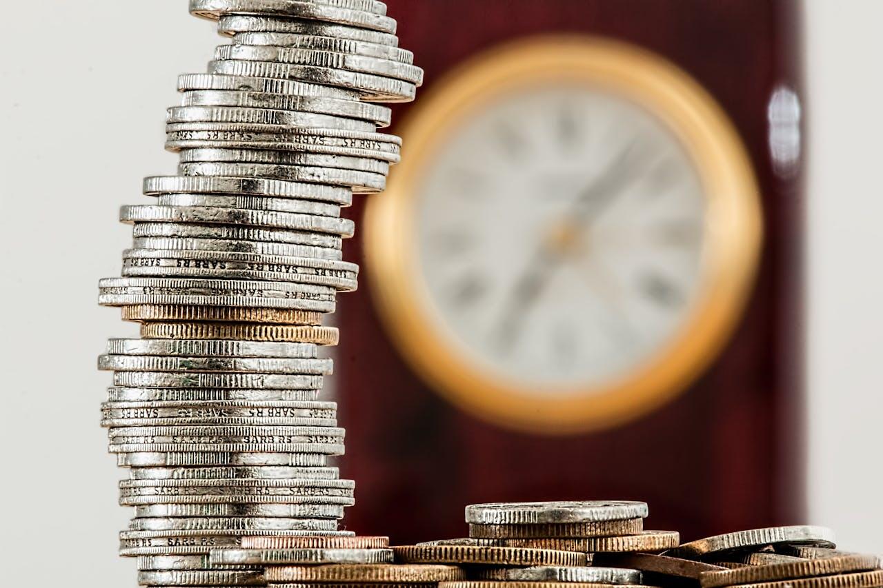 Une pile de pièces avec une horloge en fond (floue). 