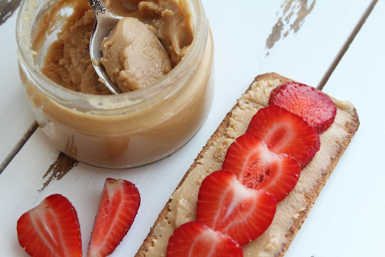 Cracotte avec du beurre de cacahuètes et des fraises découpées en morceaux. 