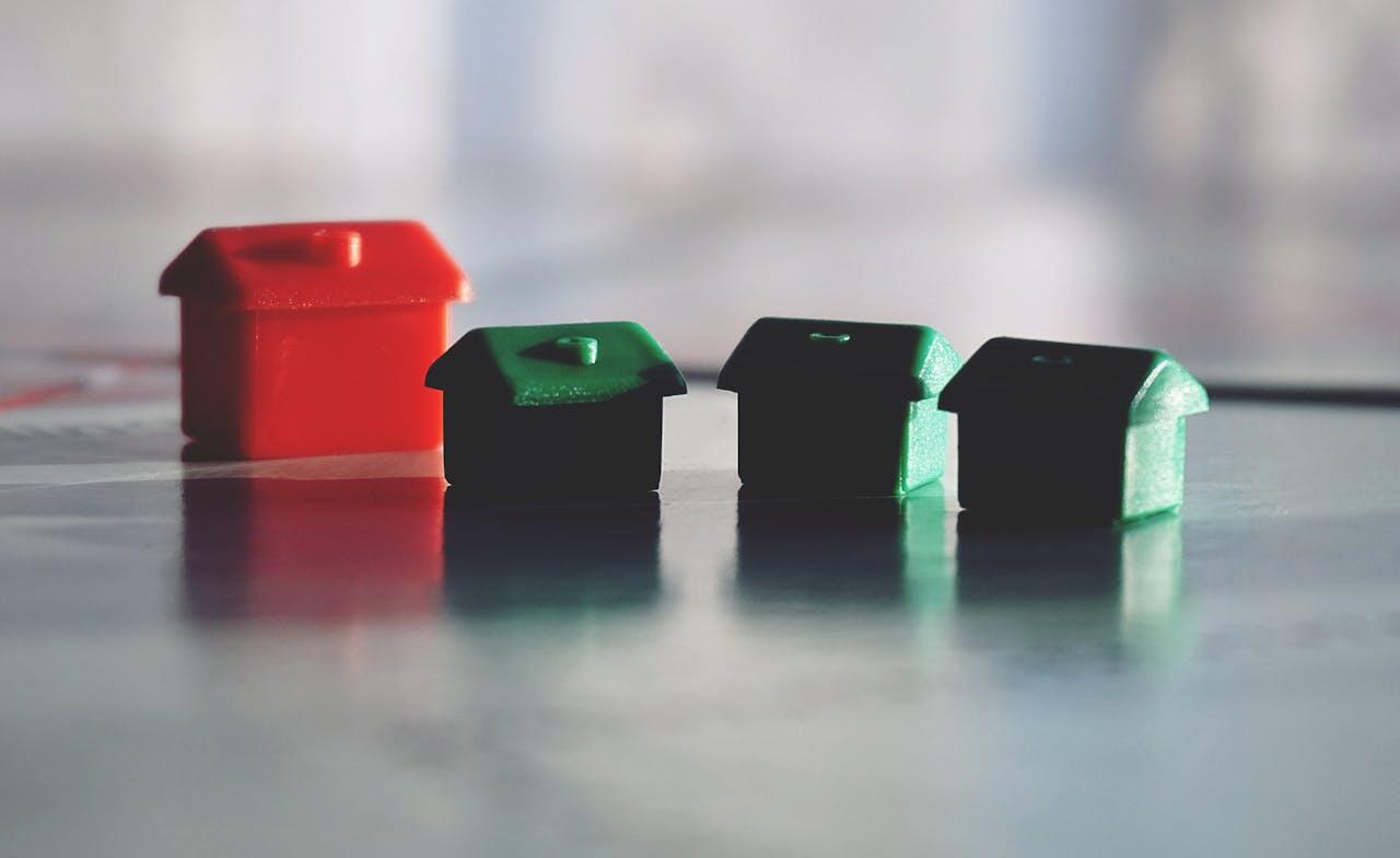 Une maison rouge et trois maisons vertes sur un plateau de Monopoly