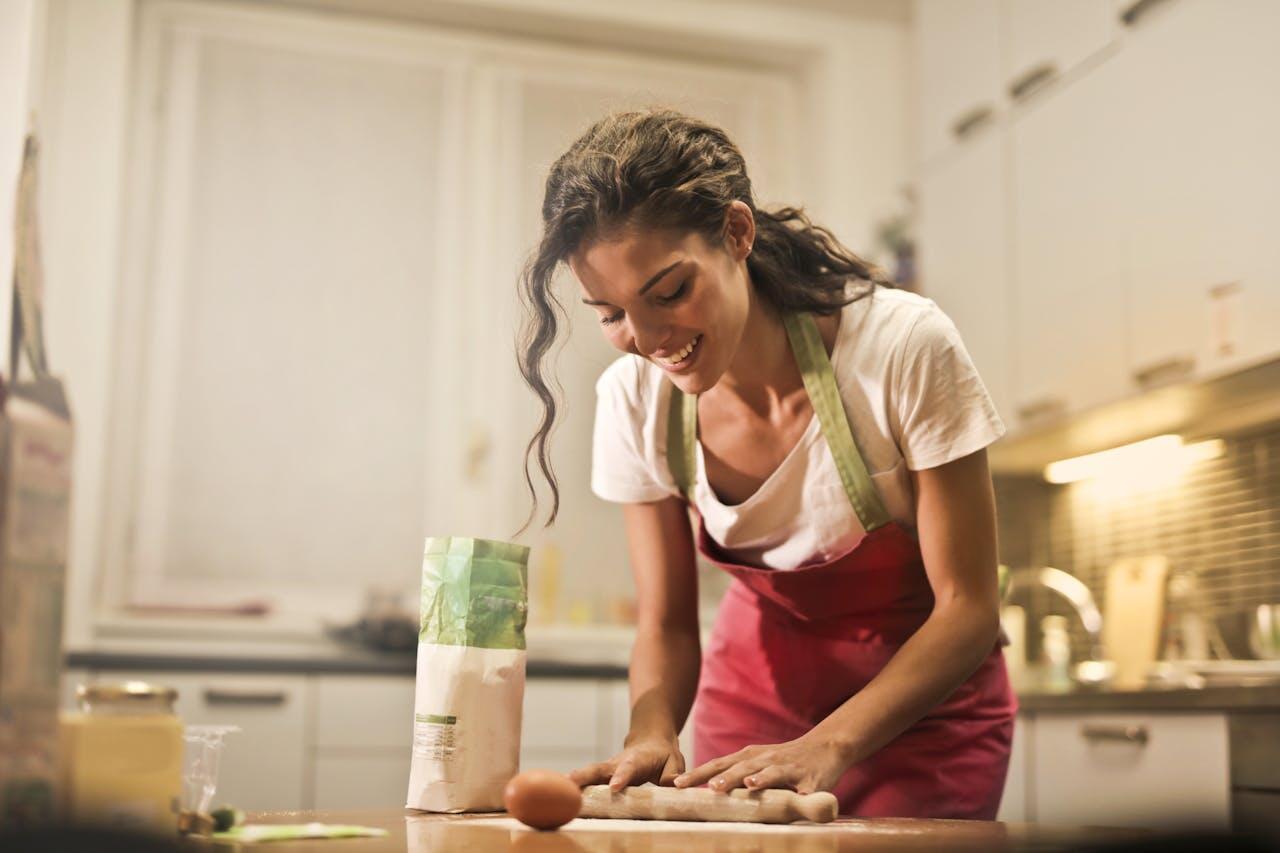Jeune femme dans sa cuisine en train de préparer un gâteau.