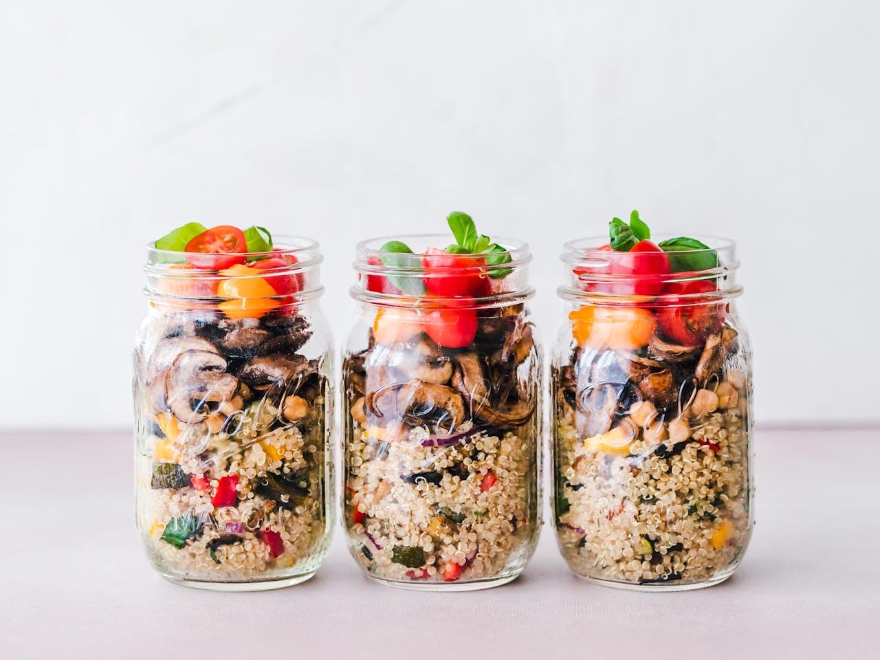 Trois bocaux remplis de salade de quinoa au poulet. 