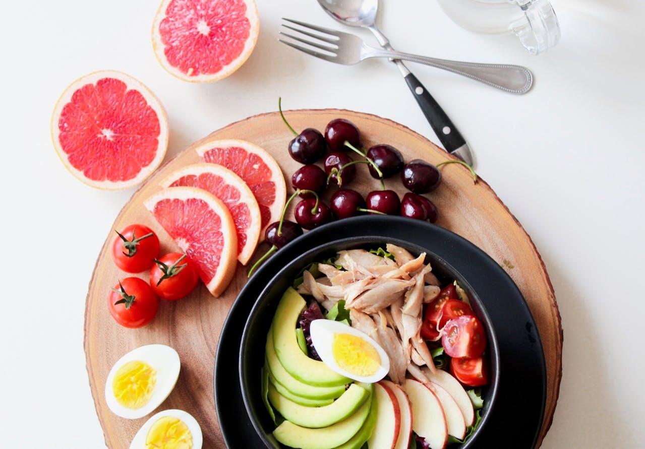 Bol d'avocats, de pommes, de tomates cerises, de salade et de poulet avec un oeuf vu du dessus. 