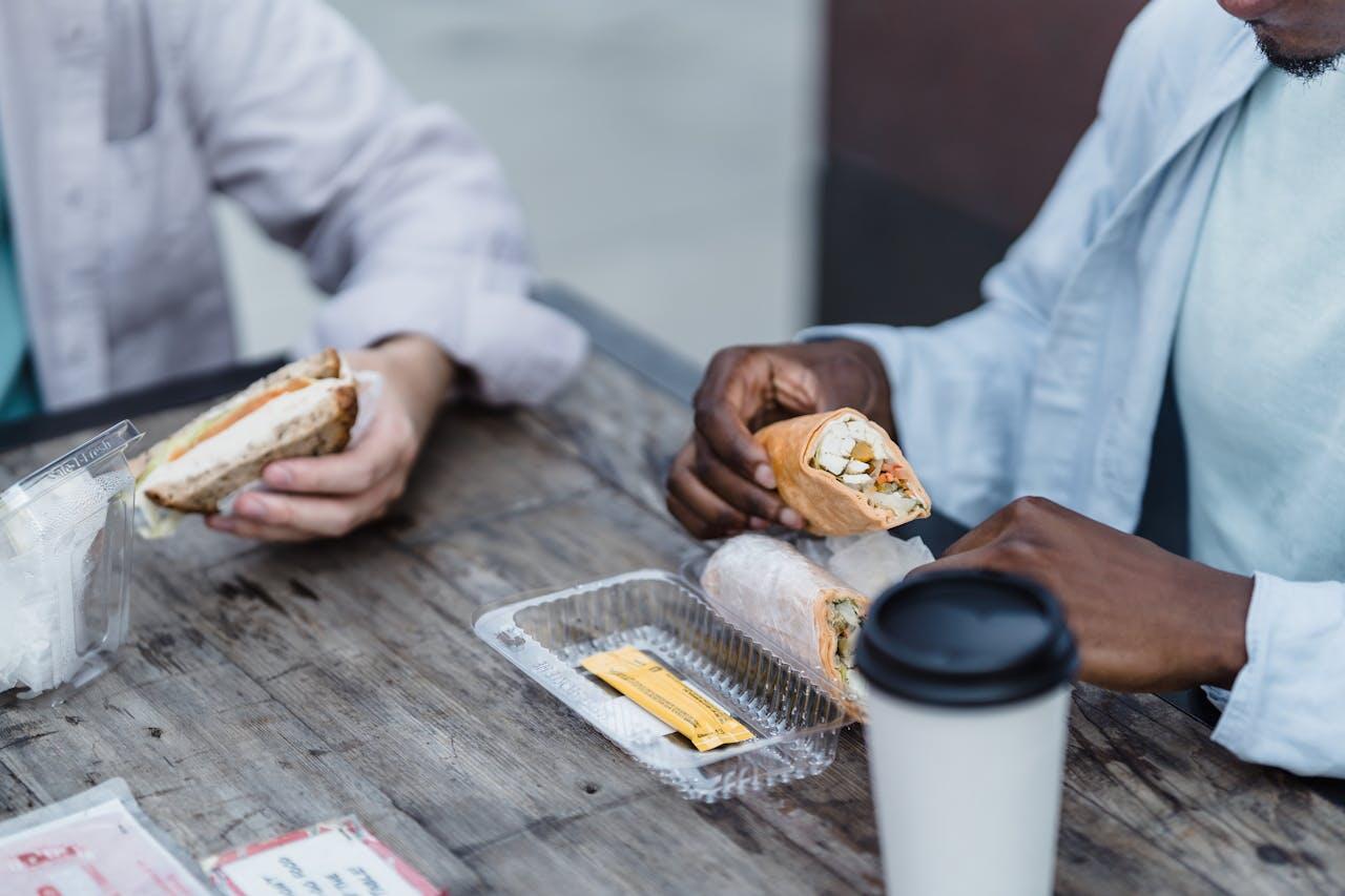 Deux hommes dégustent des wraps à table. 