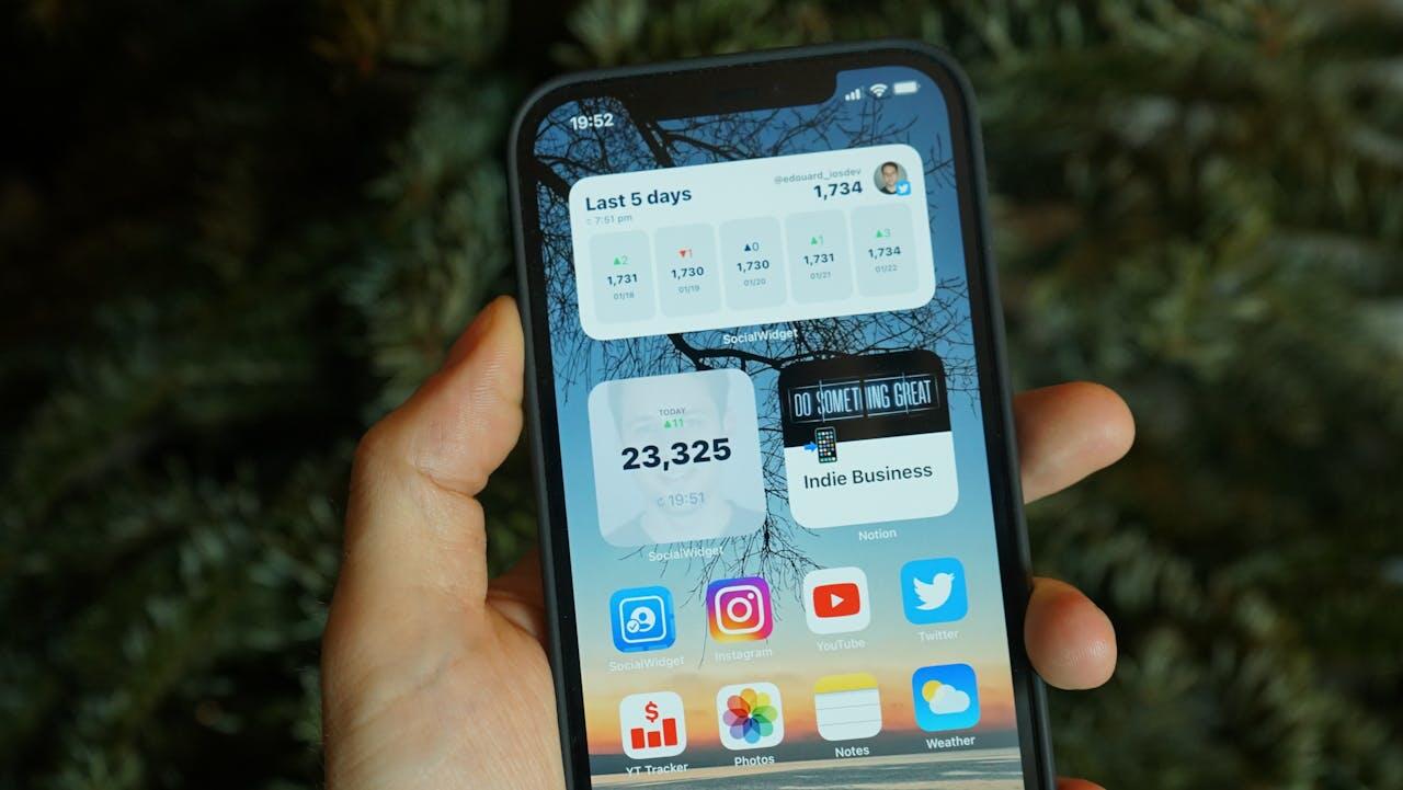 main tenant un smartphone ouvert sur l ecran d accueil
