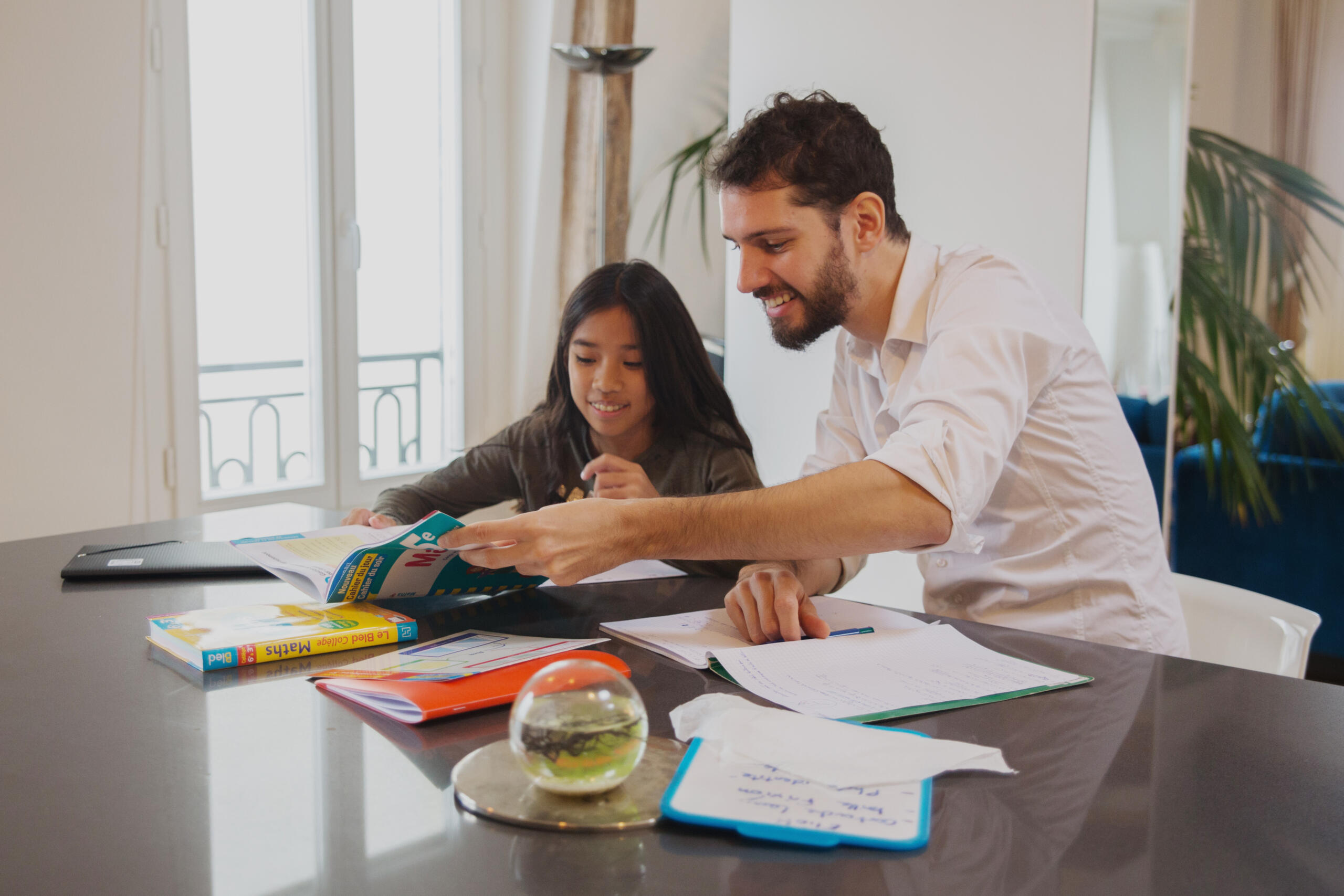 Professeur de maths de chez Superprof qui enseigne à une jeune fille chez elle. 