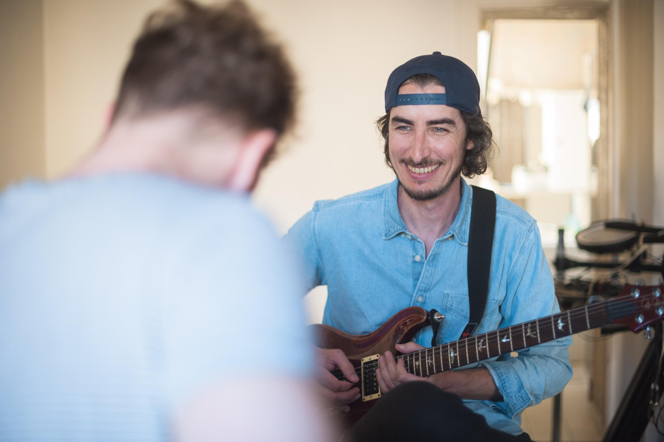 Prof de guitare souriant face à son élève.