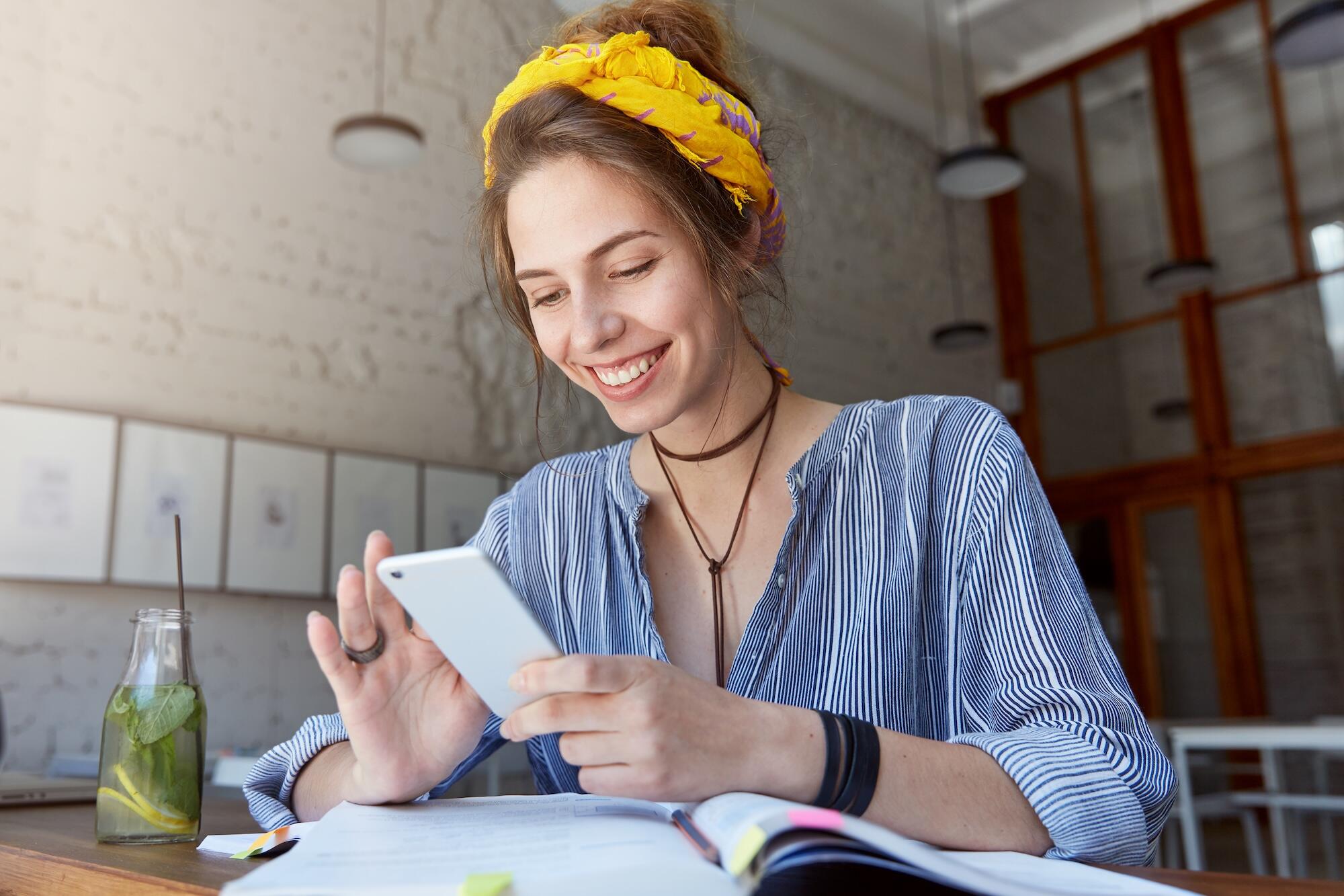Une jeune femme portant un bandana et étudiant dans un café.