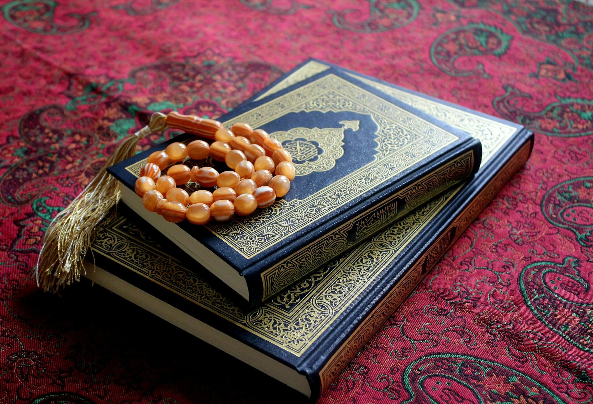 livre du Coran avec collier de prière sur un tapis de prière