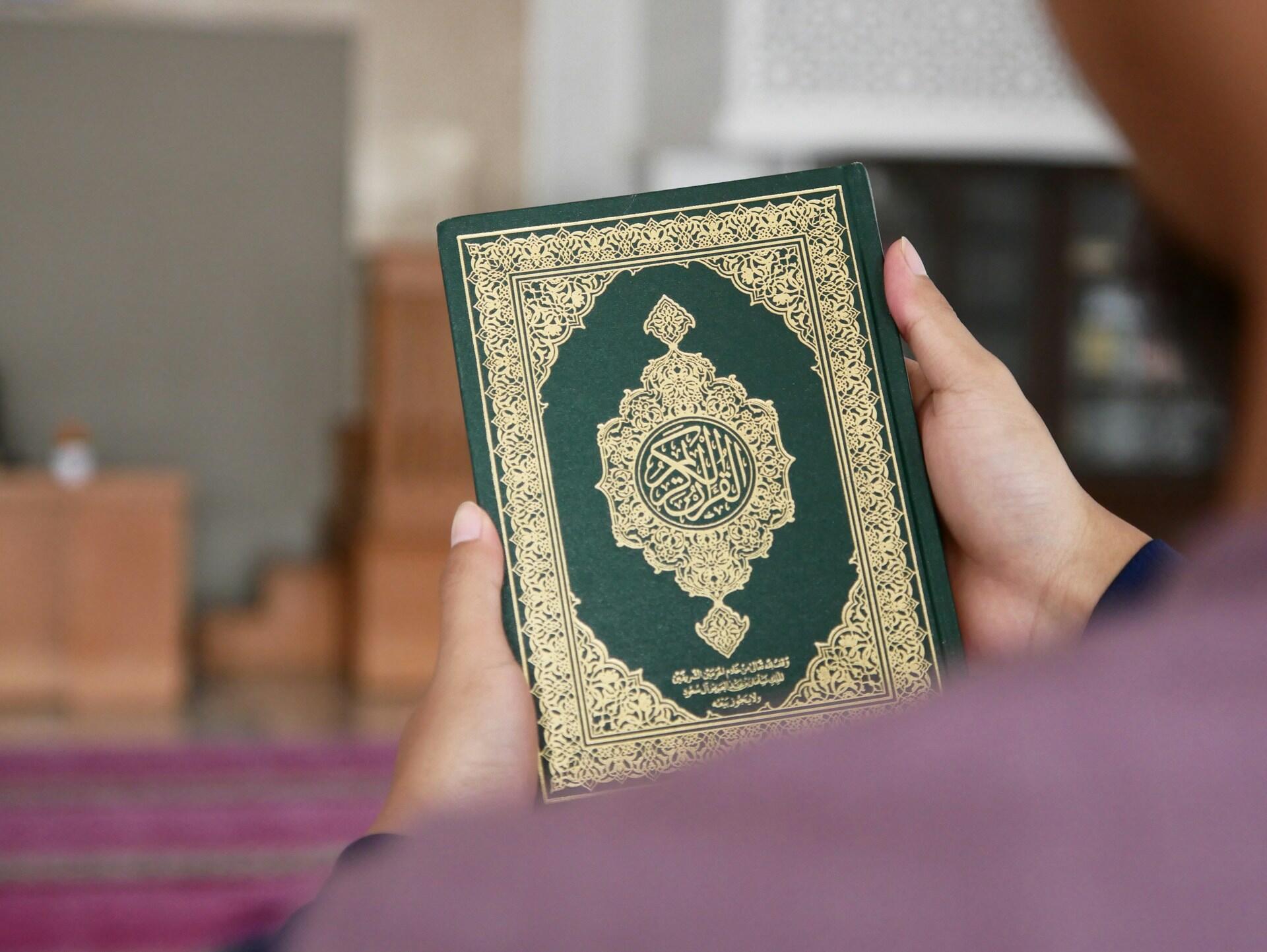 livre du Coran dans les mains d'un fidèle 