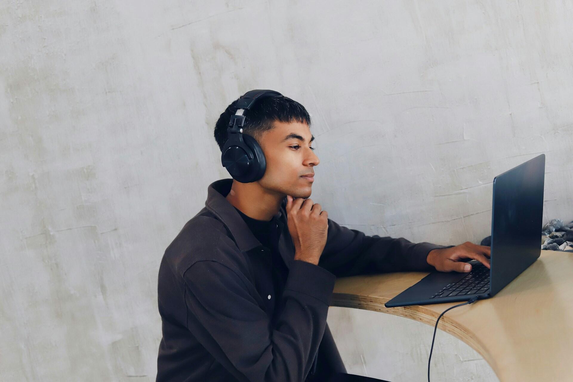 Un étudiant devant son ordinateur et avec un casque audio