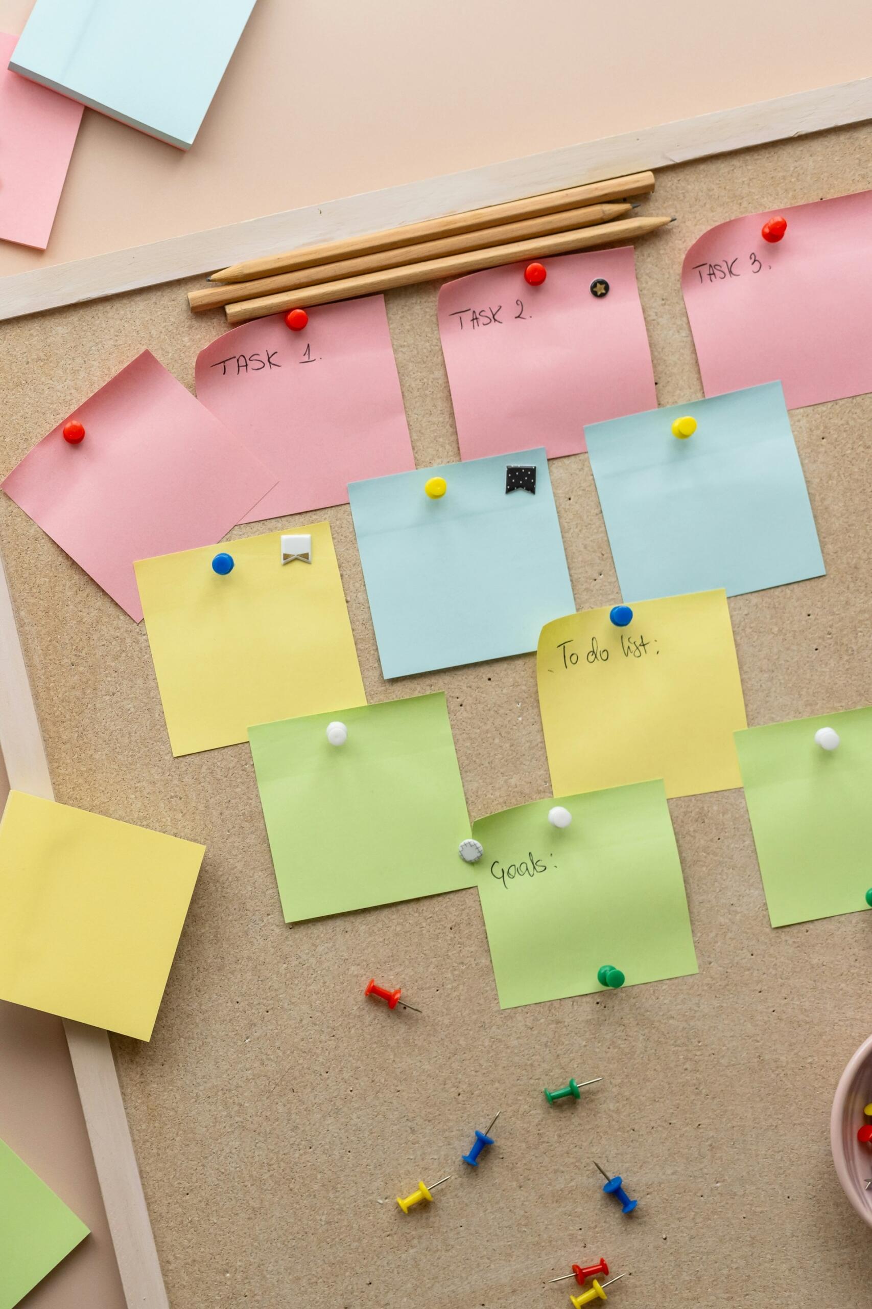 post-its colorés et pins sur une planche