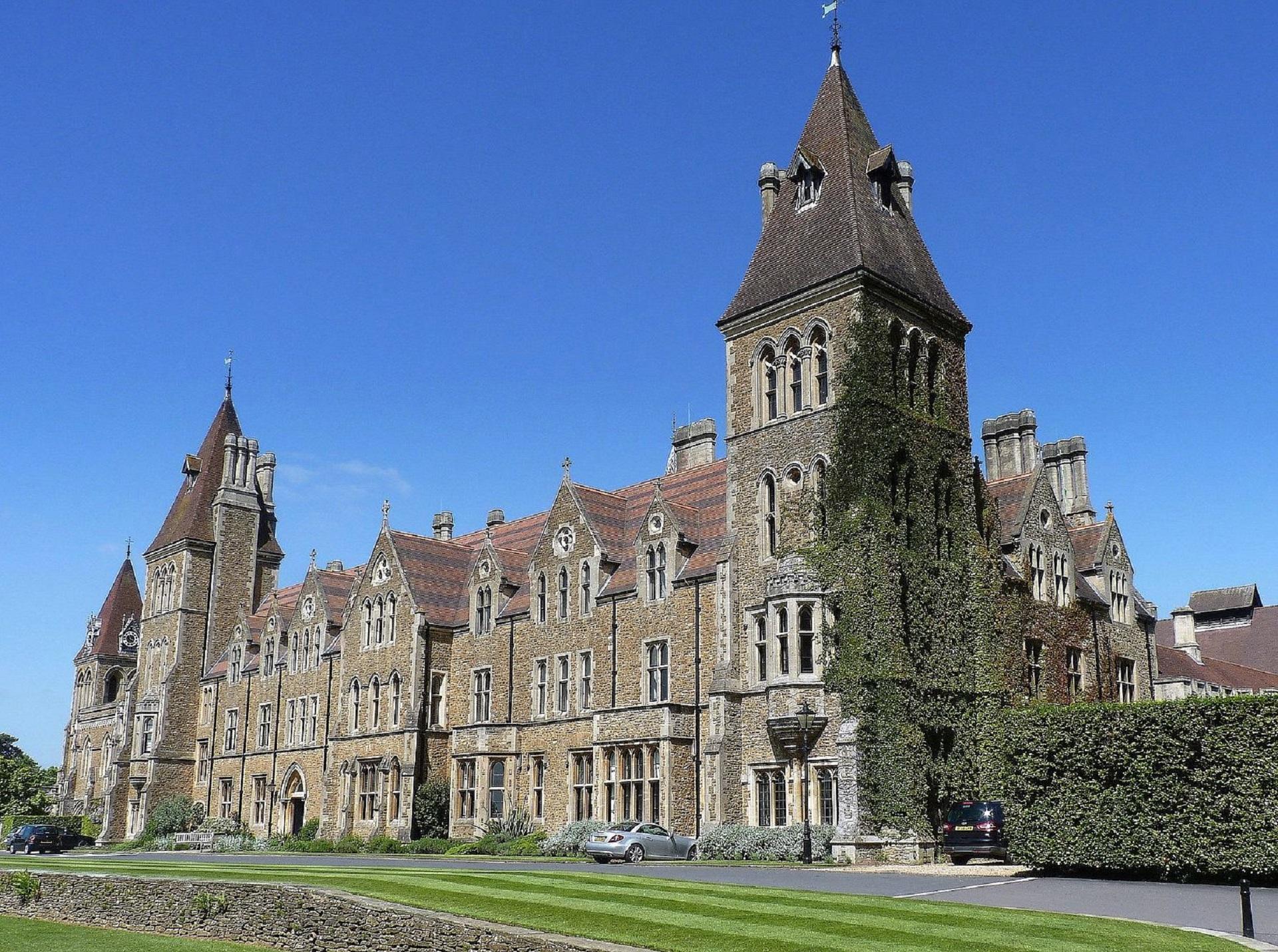 Charterhouse School hall's ivy-covered wall seen on a sunny day from across the lawn.