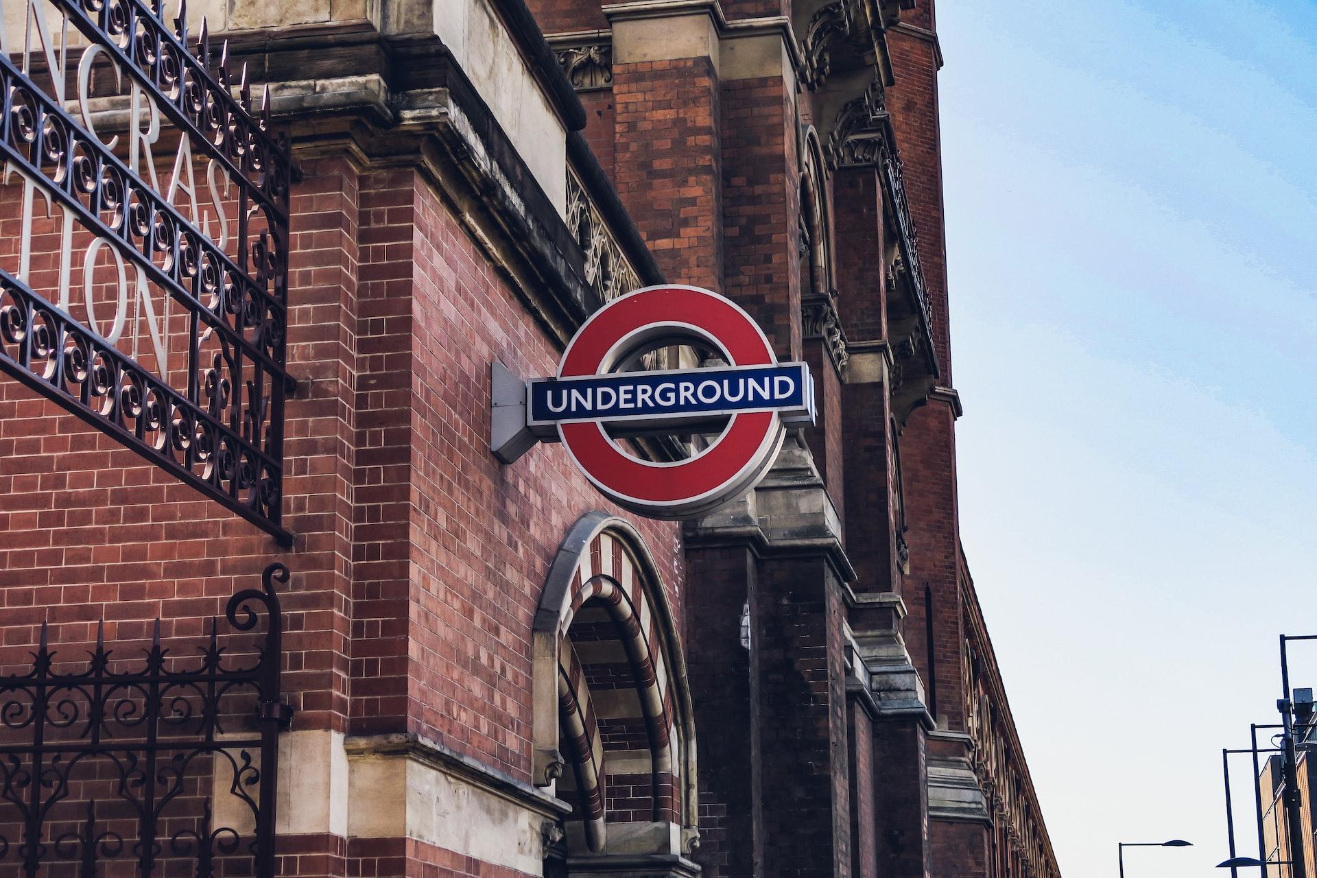 The brick facade of St Pancras railway station with a red and blue Underground sign affixed to it.