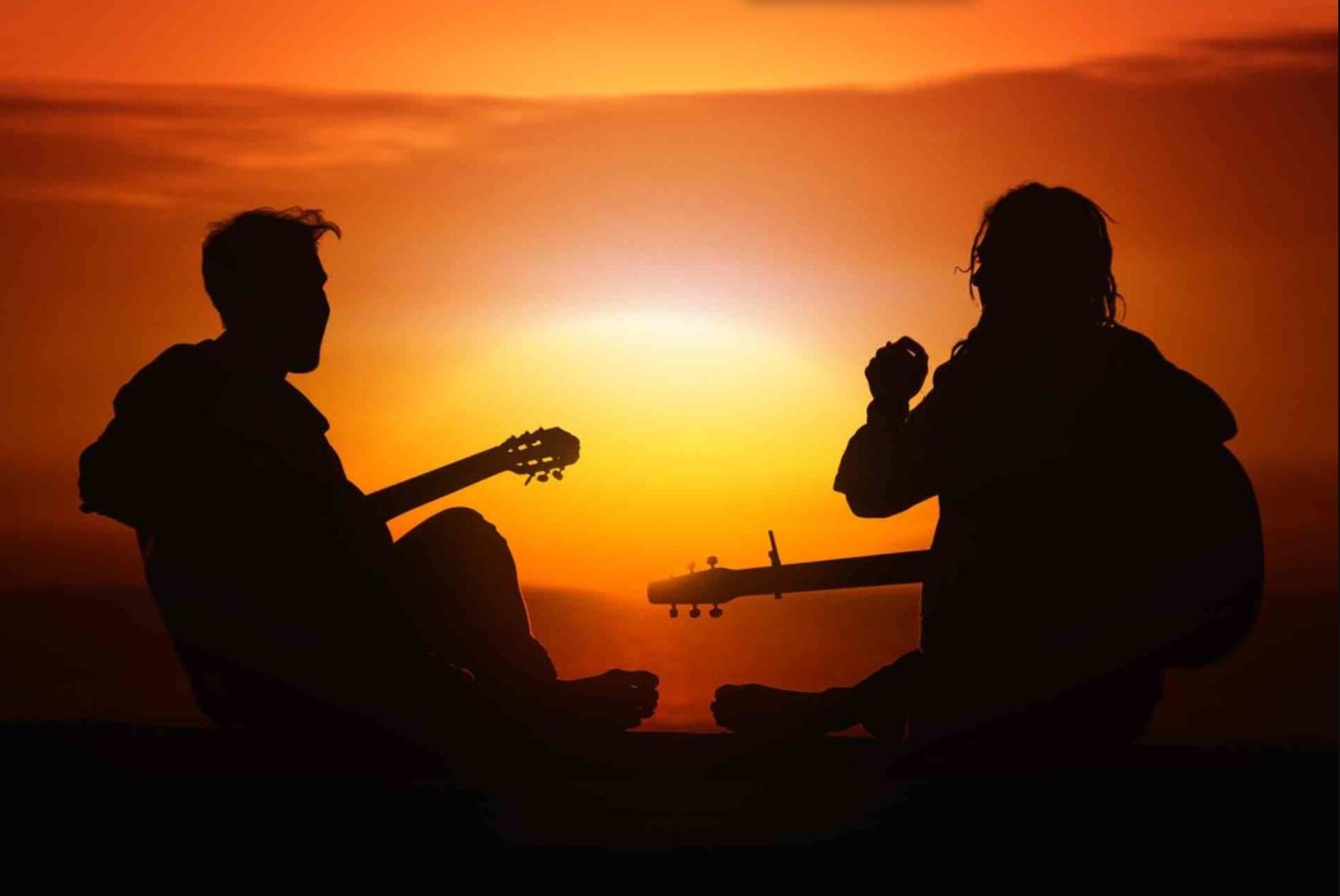 A guitar teacher gives a lesson at sunset
