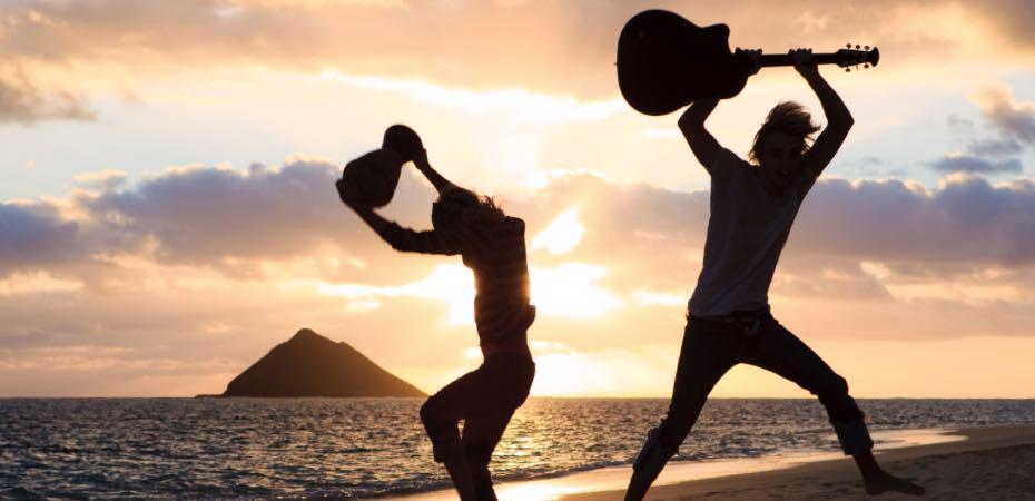 Silhouettes of men with guitars against the sunset