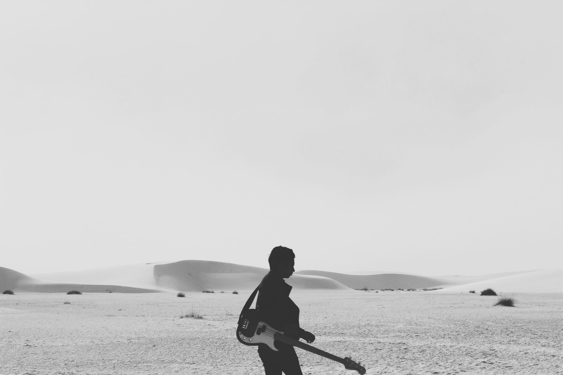 A man in a white field with guitar.