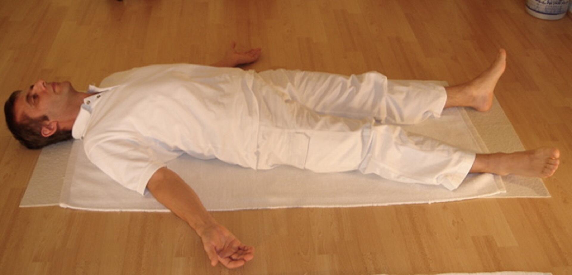 A man wearing white laying on the floor on his back.