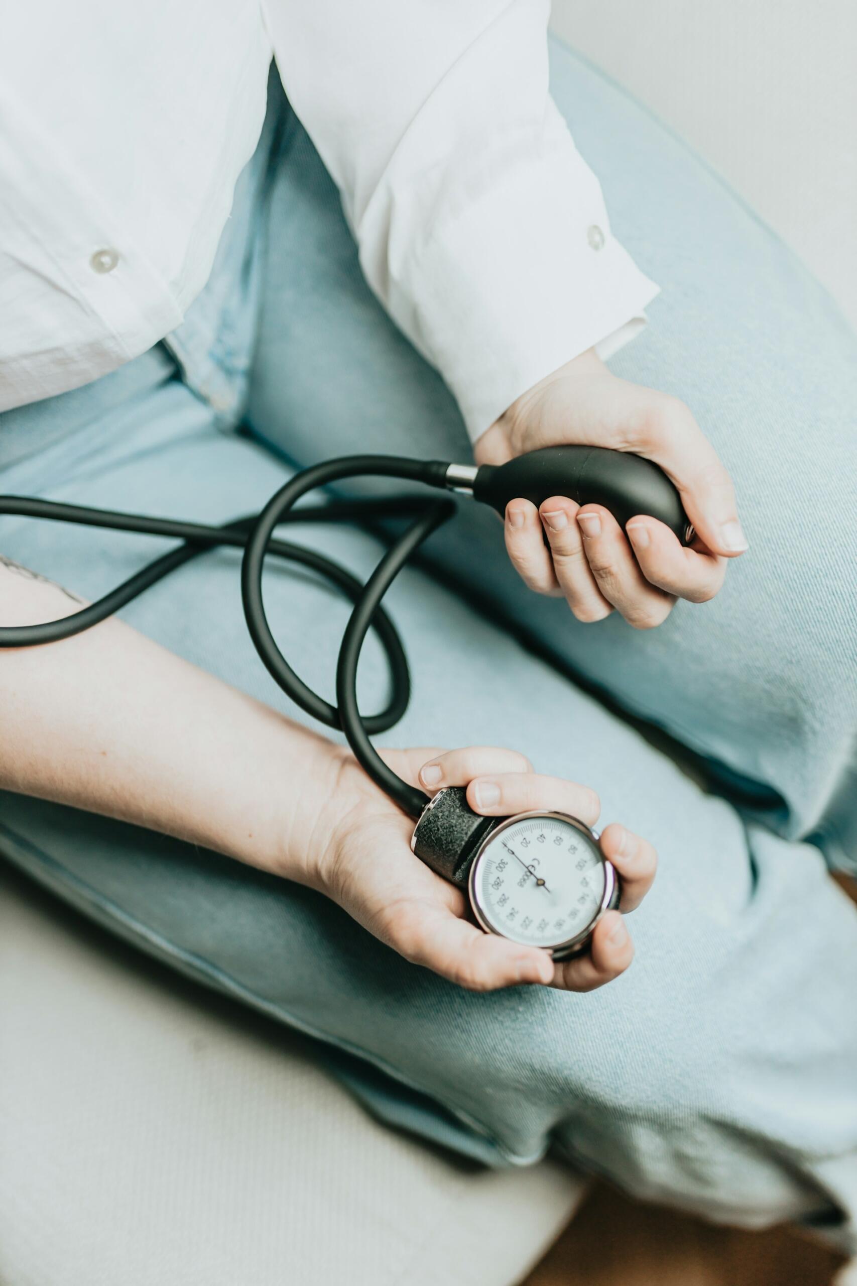 A close-up of hands holding a blood pressure gauge and cuff, with a focus on the measurement dial.
