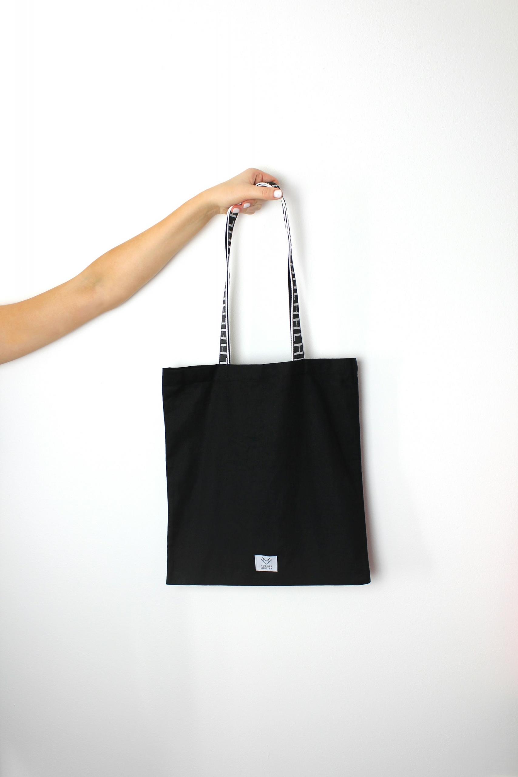 hand holding up a simple black tote bag