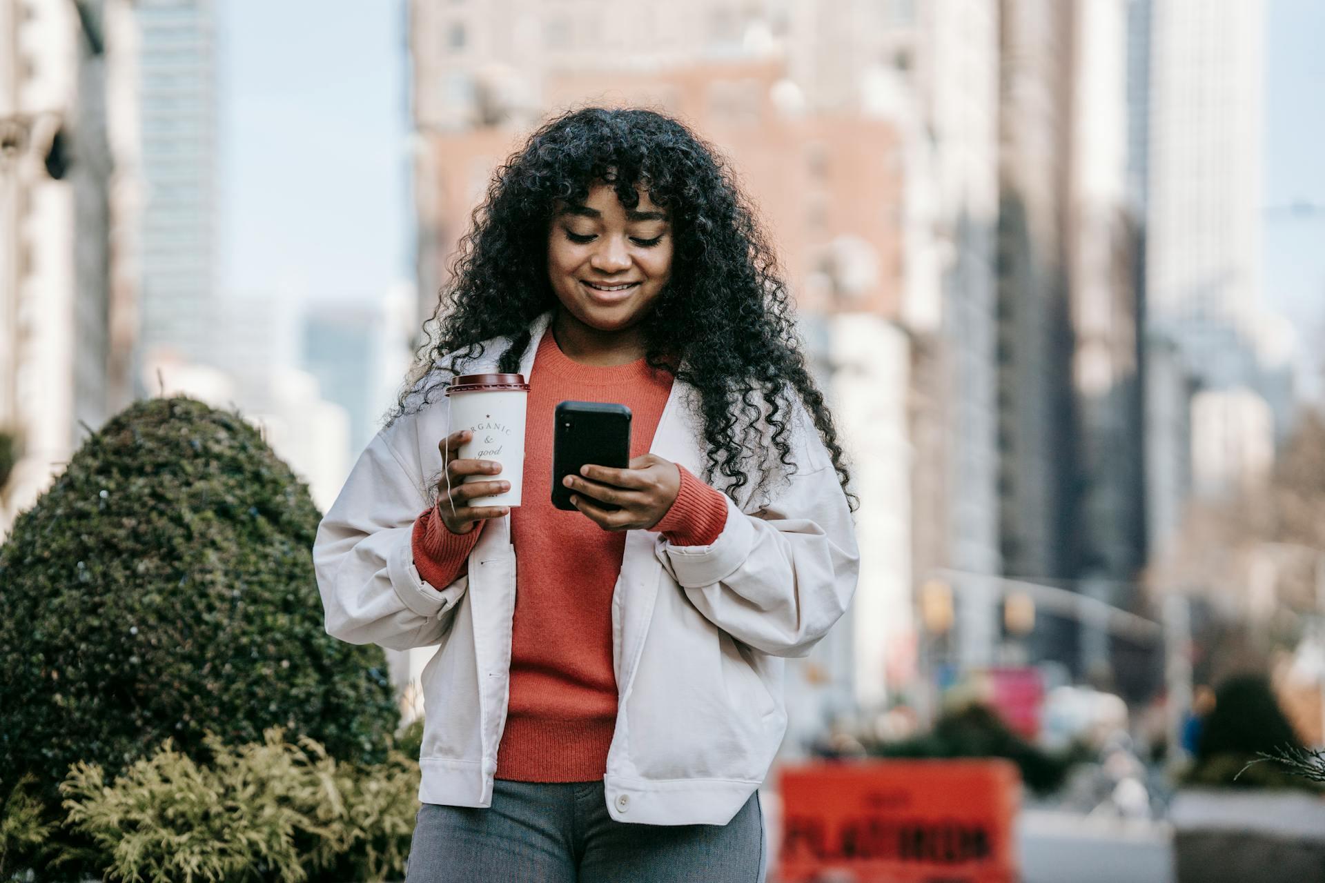 woman looking at her phone while walking on the street