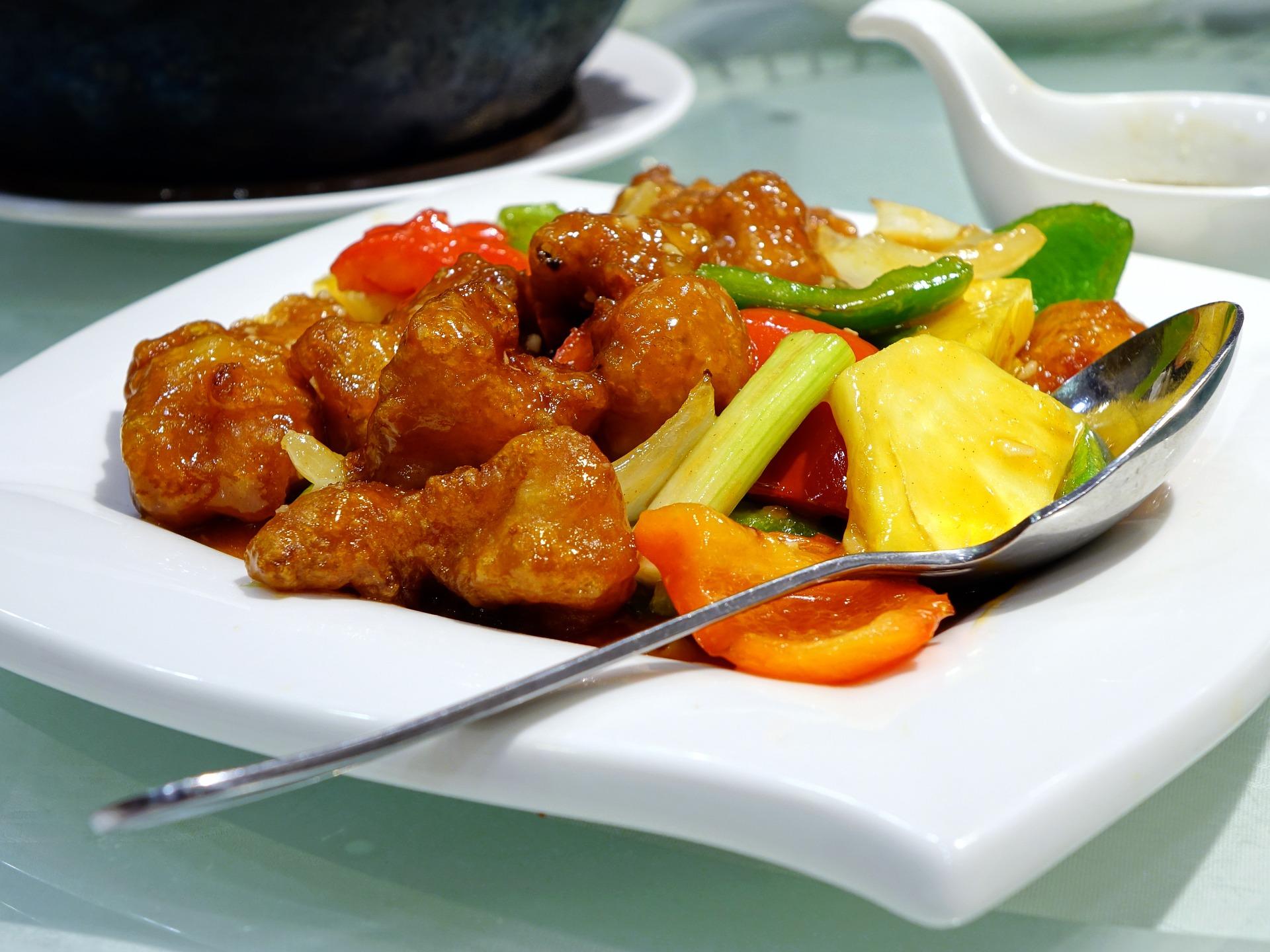Sweet and sour pork garnished with vegetables and pineapple.