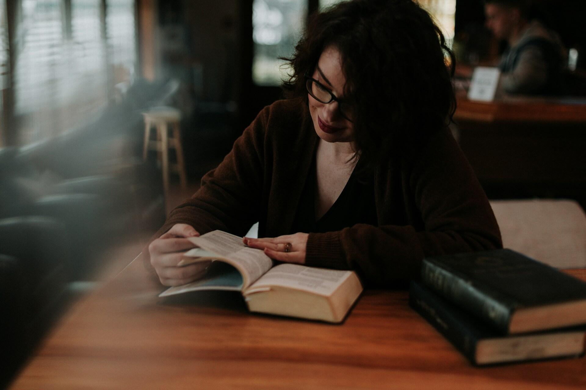 woman sitting at a desk reading a novel