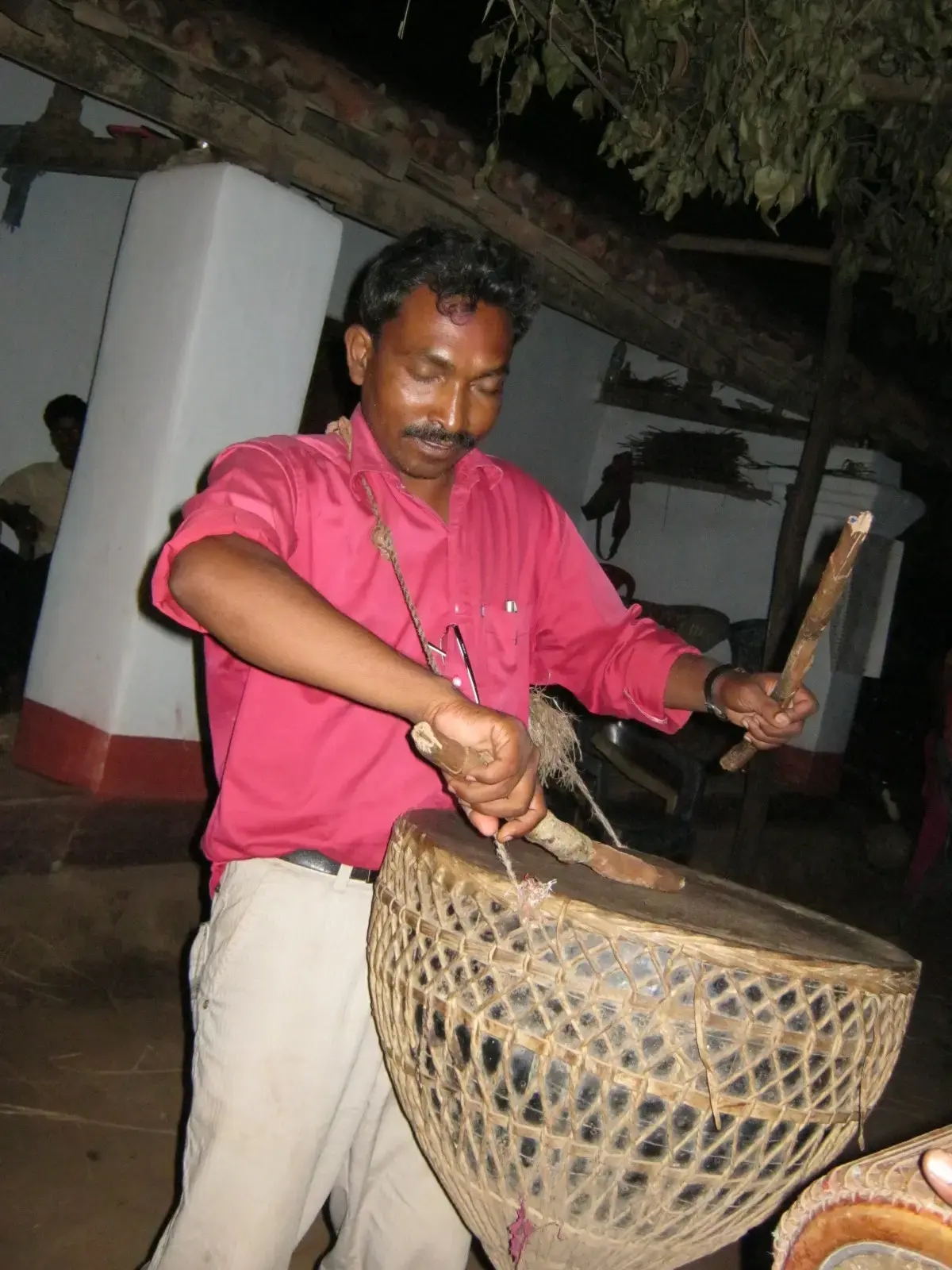 man in red shirt playing a tamak drum