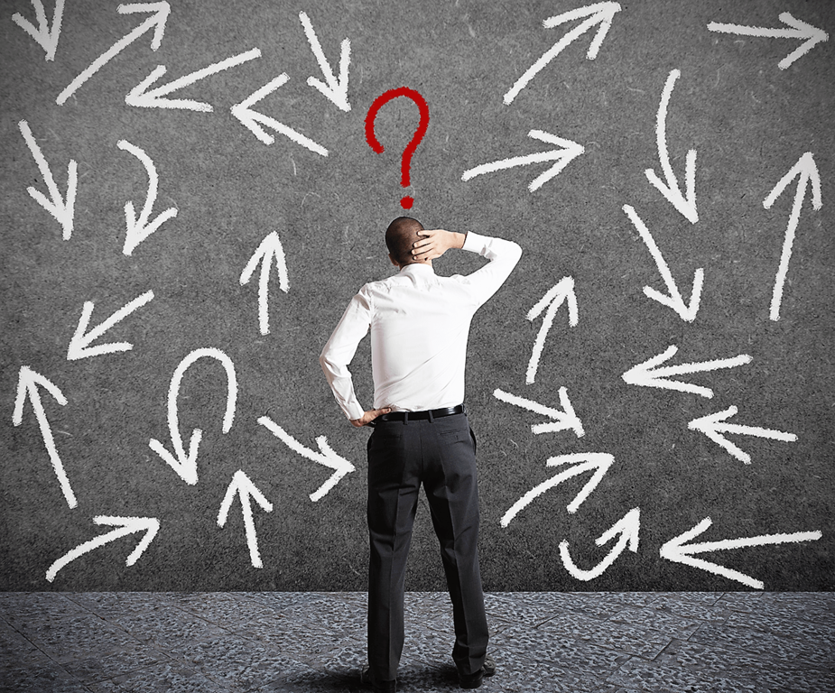 A man in a suit facing a chalkboard covered with white arrows, with a red question mark above his head. The art of making decisions is studied in behavioural economics.