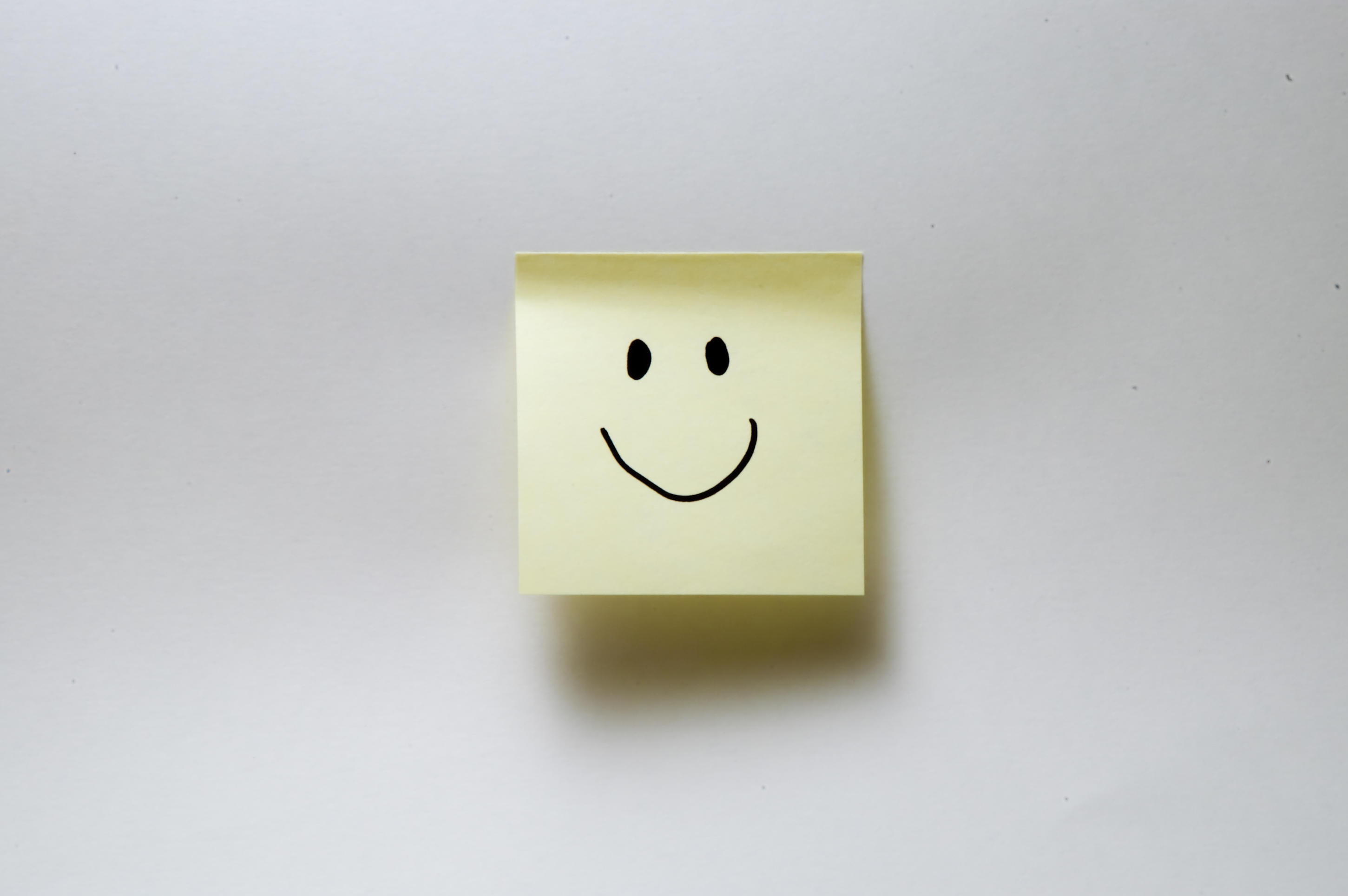 A post-it note with a smiley face against a grey background. Happy Thought is one poem you could read to your children.