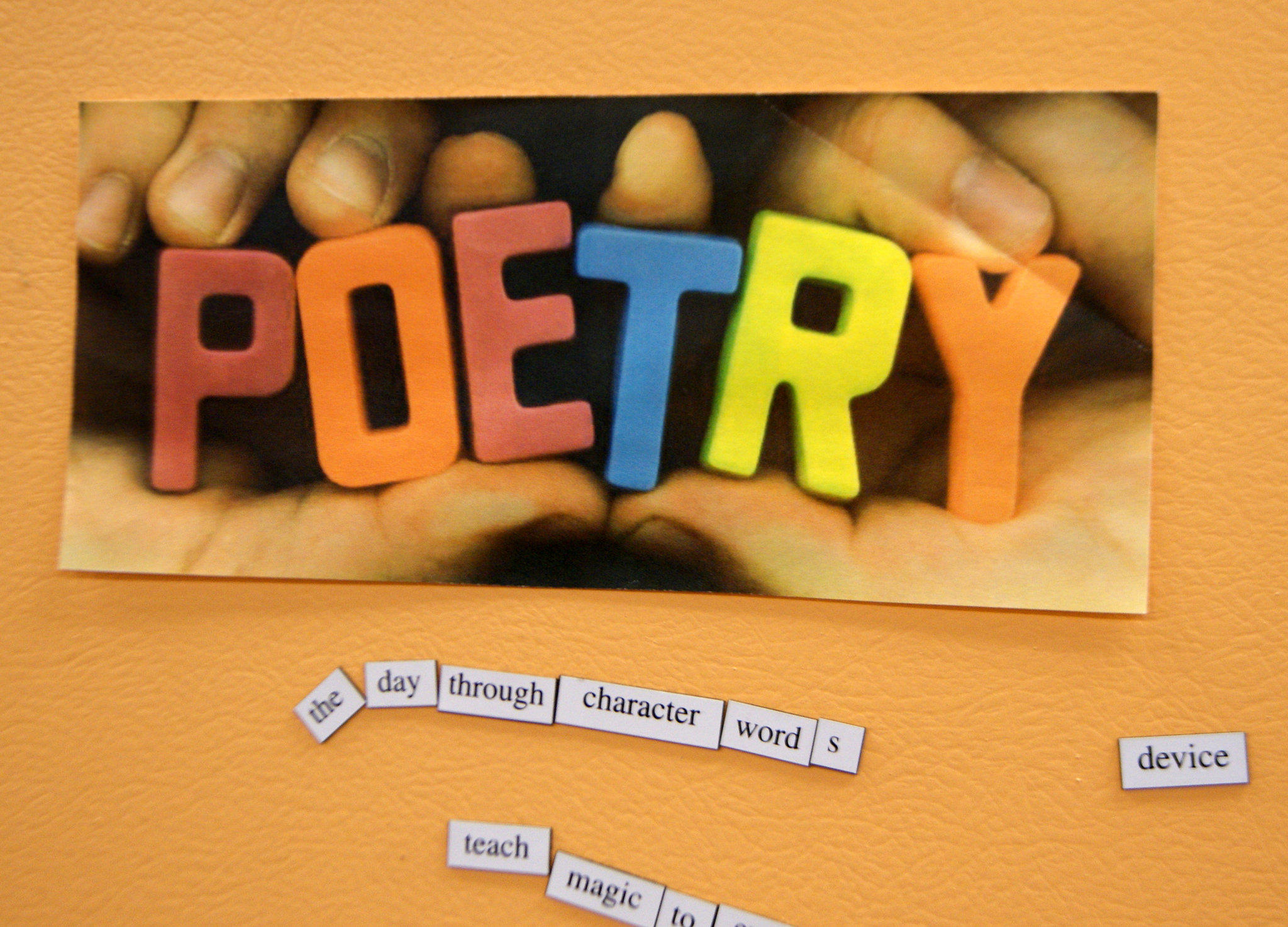 A photo of hands holding words that spell out poetry. The photo is on an orange background, and magnetic words are below the photo. Poetry books for kids can often be found in libraries. 